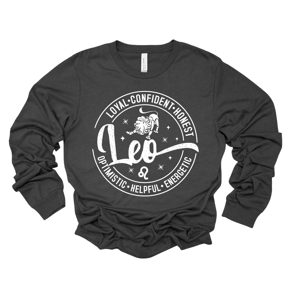 Woman wearing a vibrant dark heather grey Leo zodiac t-shirt featuring a white round graphic with a lion illustration, the word "Leo," and positive trait keywords like loyal, confident, honest, energetic, helpful, and optimistic.