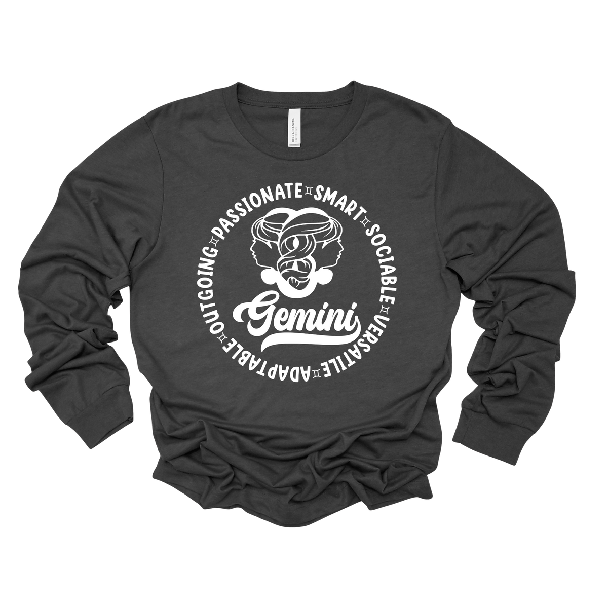 A dark charcoal gray long-sleeve t-shirt with a white graphic print on the front. The graphic features a circular design with the word 'Gemini' in script, a central illustration of a Gemini zodiac sign, and surrounding adjectives like 'PASSIONATE', 'SMART', 'SOCIAL', and 'LEADABLE' printed in a circle.
