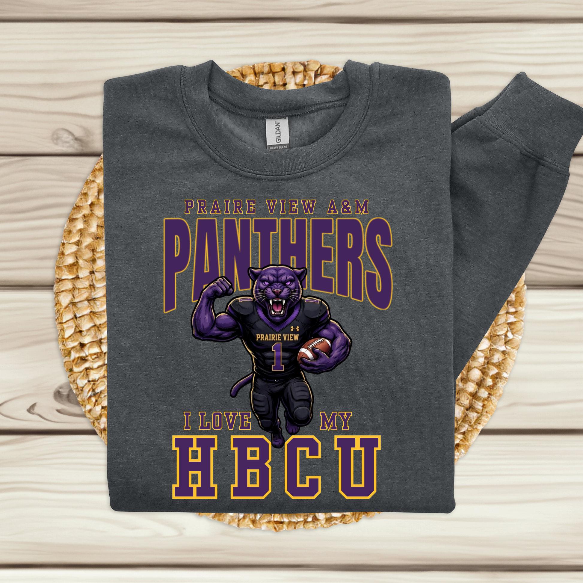 A dark gray sweatshirt with a 'Prairie View A&M Panthers' graphic, displayed flat on a woven placemat over a light wood background.