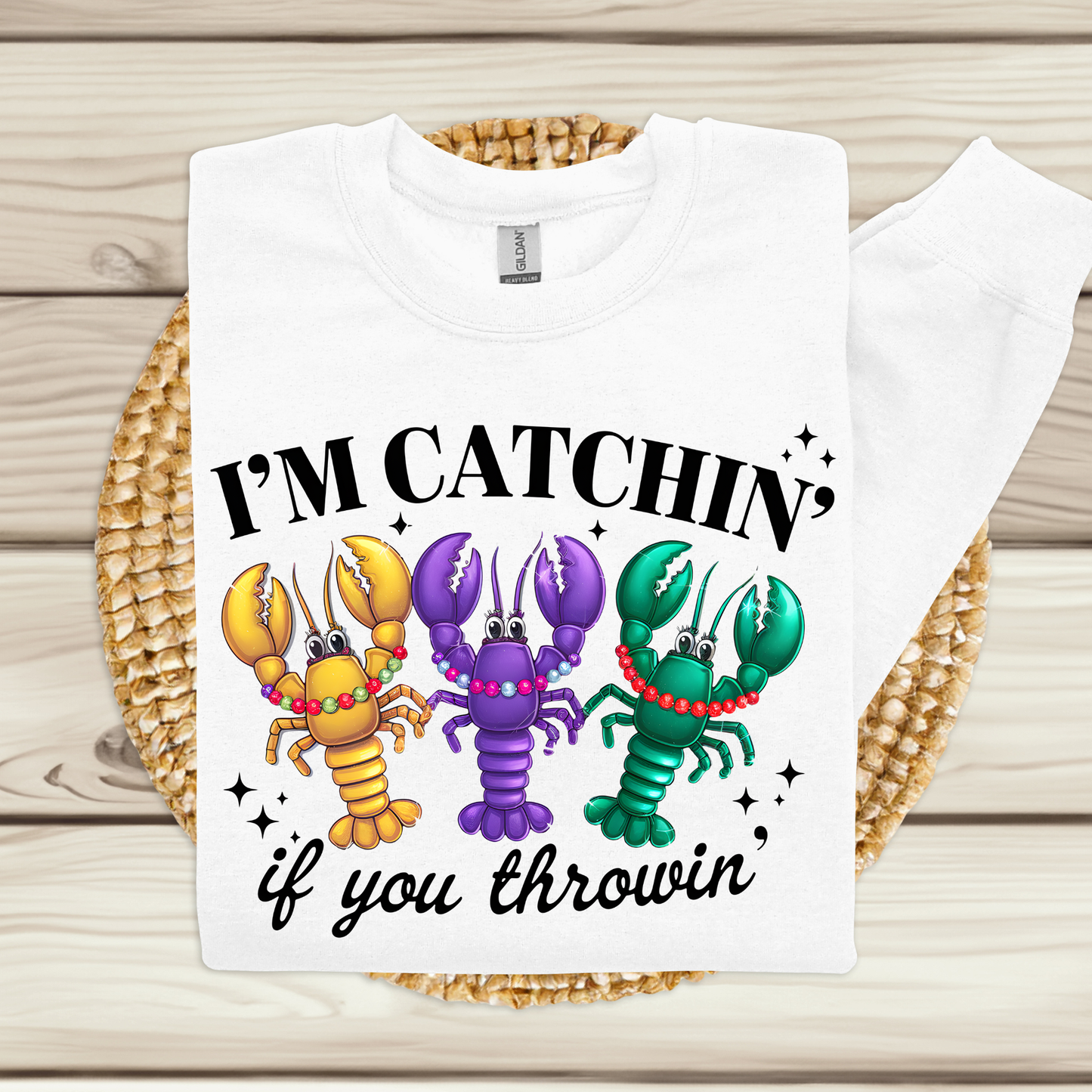 White t-shirt with colorful lobster design and text on a wooden surface