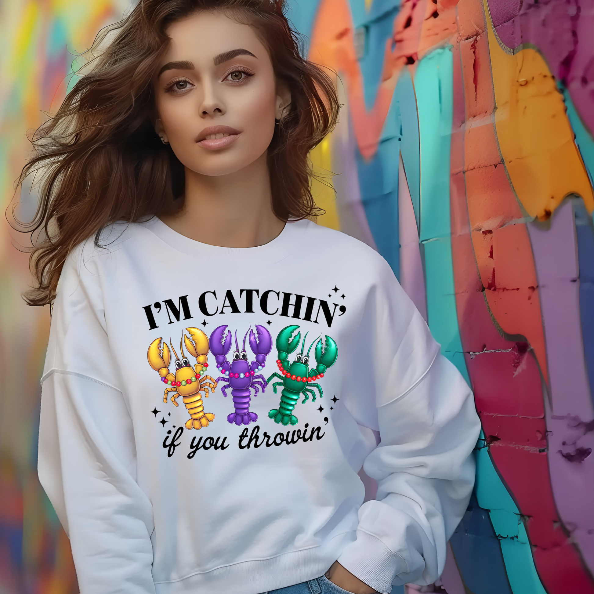 Woman wearing a white sweatshirt with colorful lobster graphics and text against a multicolored background.