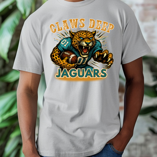 Gray t-shirt with a jaguar graphic and 'Claws Deep Jaguars' text, worn by a person.  Jaguars Football Graphic Tee: Claw Deep Jaguars Game Day Comfy T-Shirt