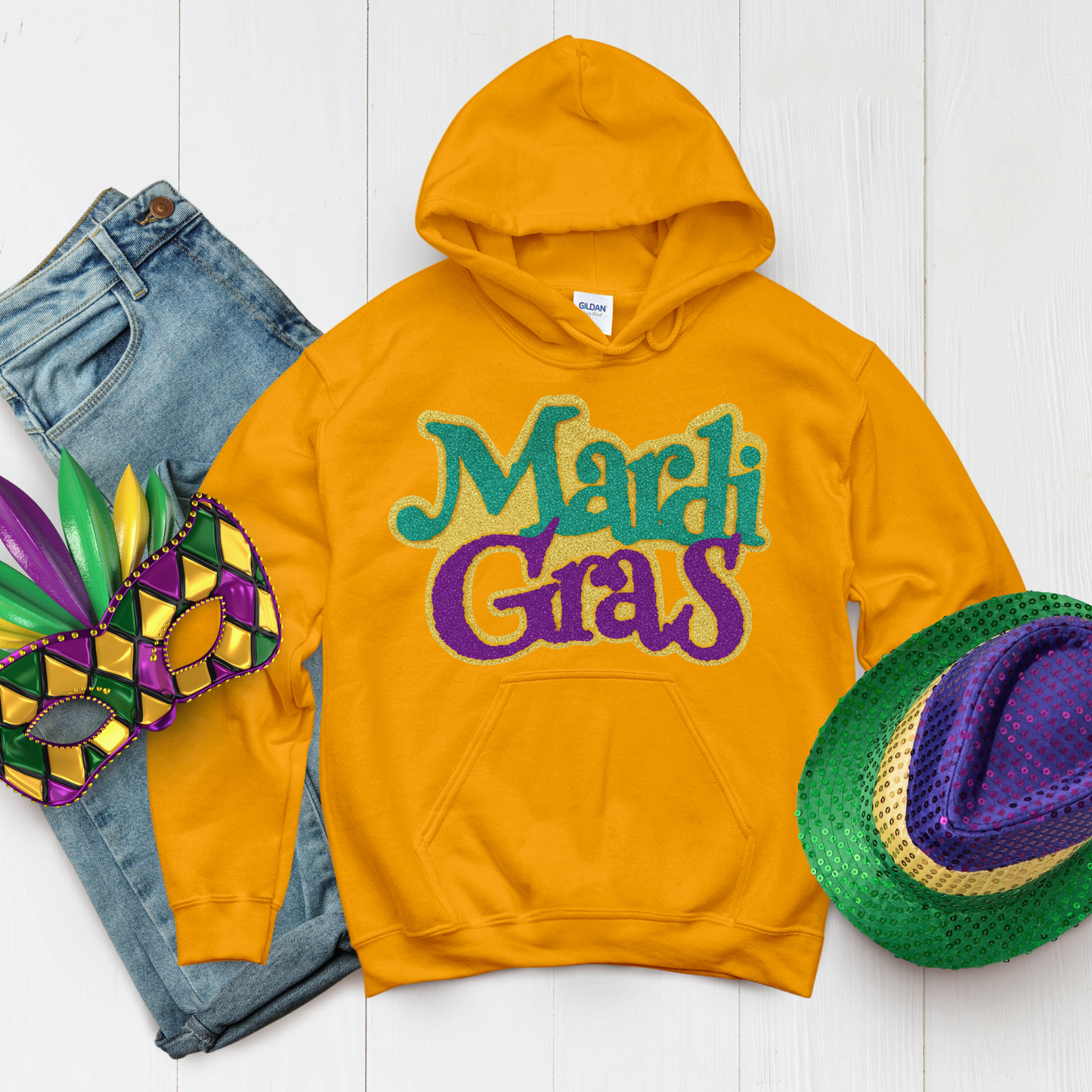 Yellow hoodie with 'Mardi Gras' text, jeans, mask, and hat on a white background