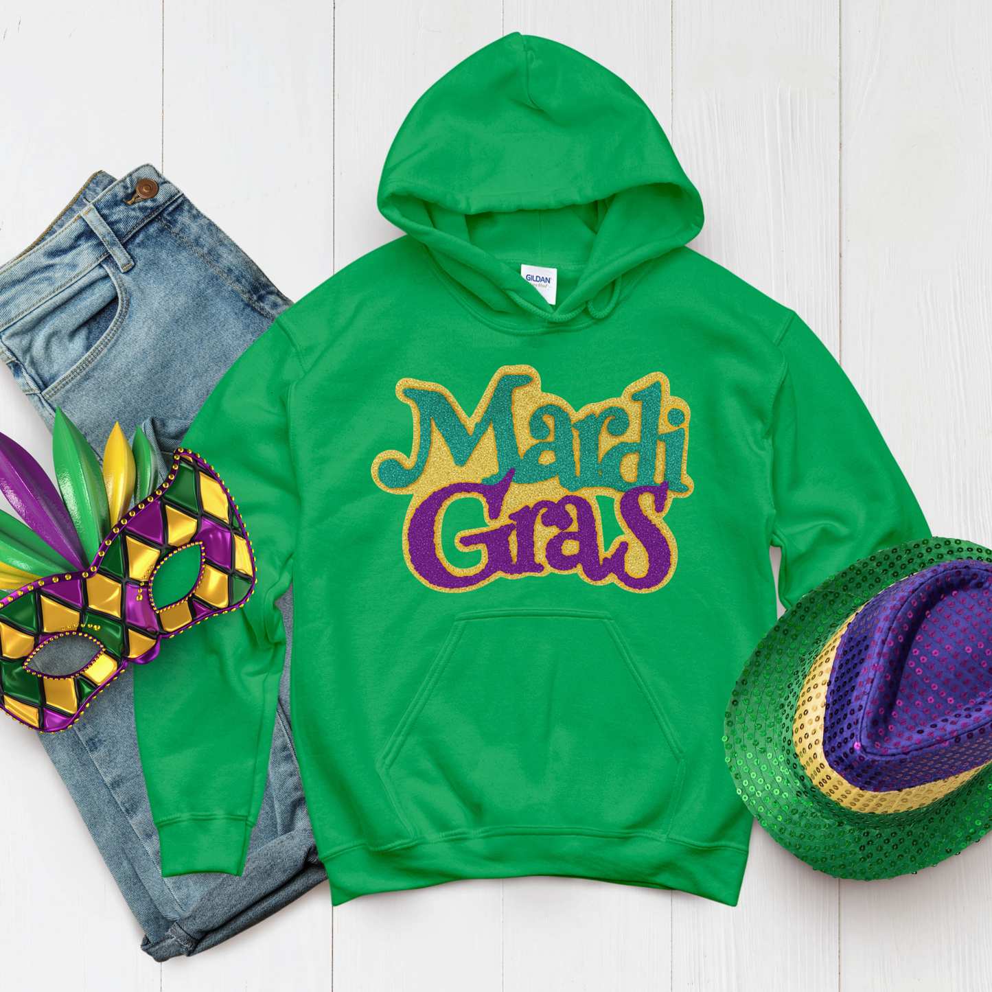 Green hoodie with 'Mardi Gras' text, jeans, mask, and hat on a white background