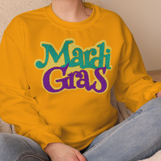 Person wearing a yellow sweatshirt with 'Mardi Gras' text in colorful letters.