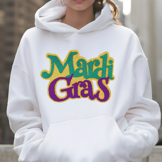 White hoodie with 'Mardi Gras' text in colorful letters on a blurred background