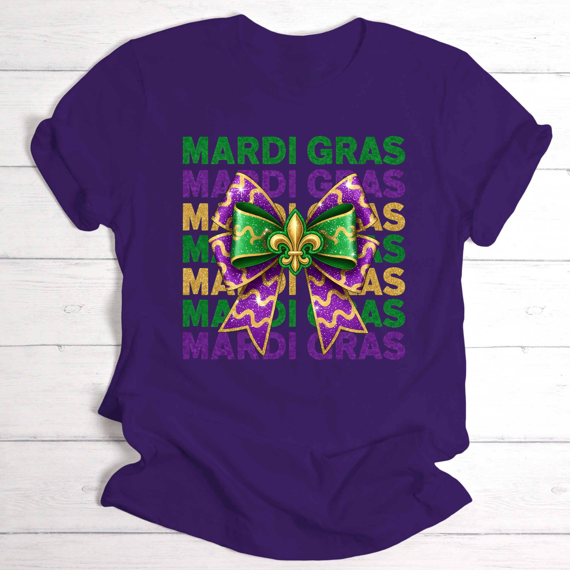 Purple t-shirt with Mardi Gras-themed design featuring a bow and text on a wooden surface.