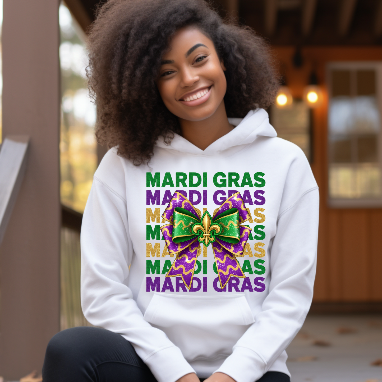 Person wearing a white hoodie with Mardi Gras-themed design outdoors.