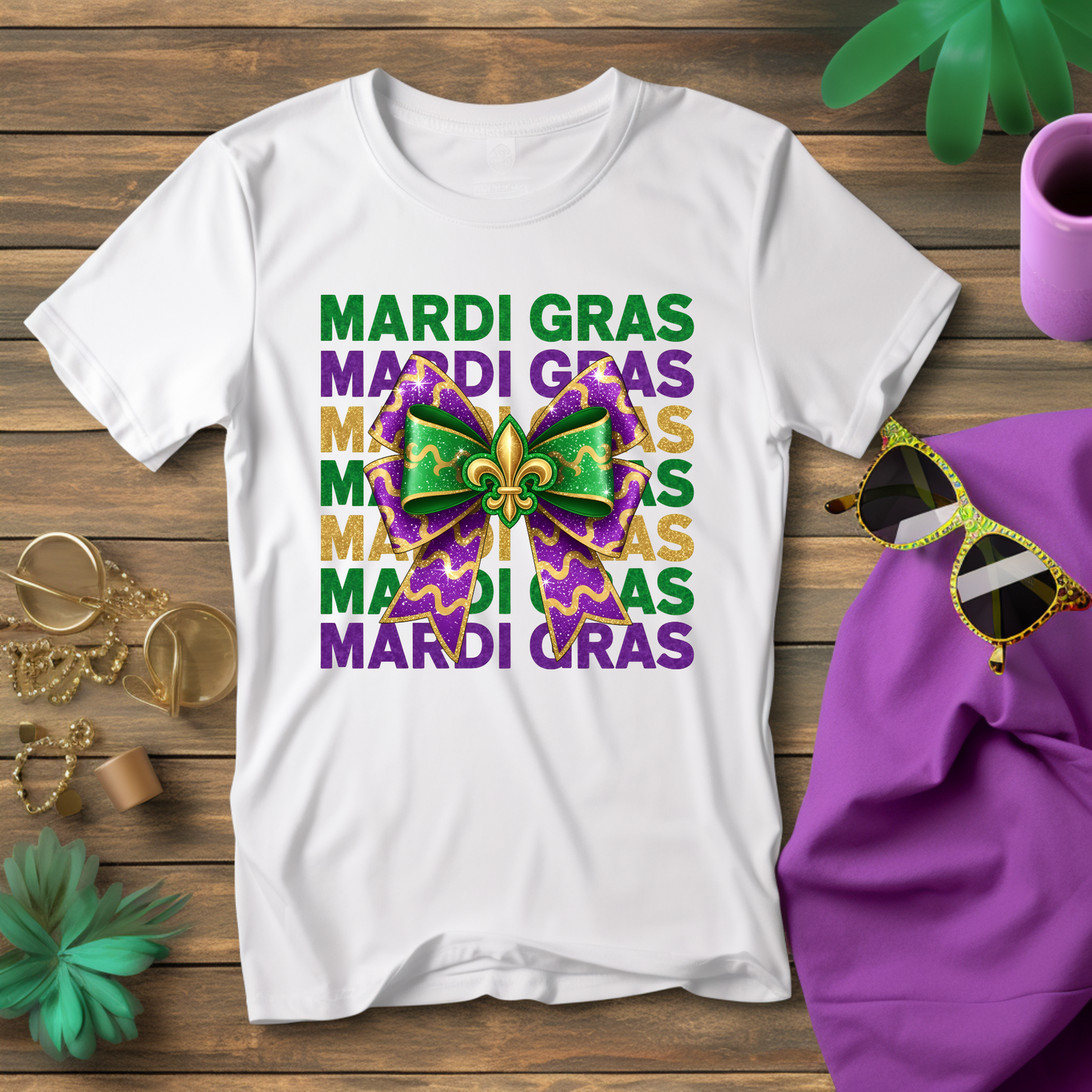White t-shirt with Mardi Gras-themed design on a wooden surface with sunglasses and a hat.