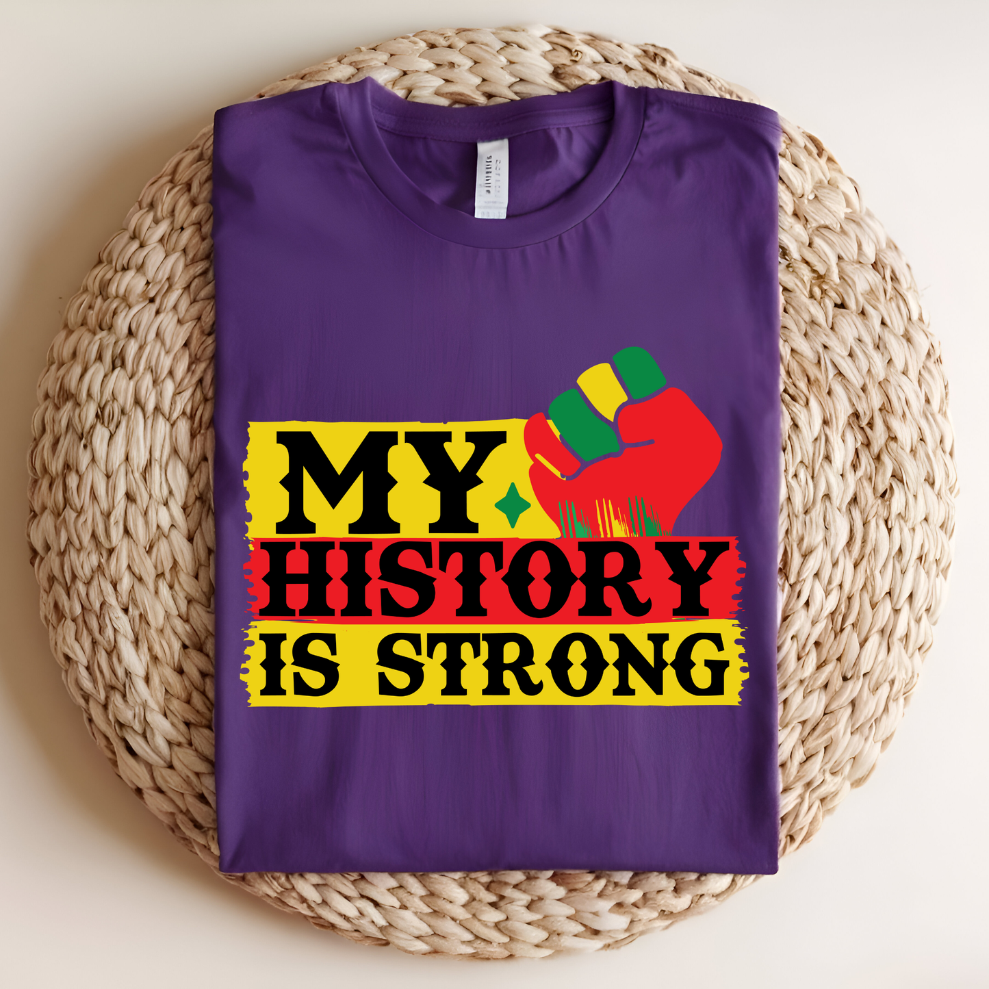 Purple t-shirt with 'My History is Strong' design on a woven mat