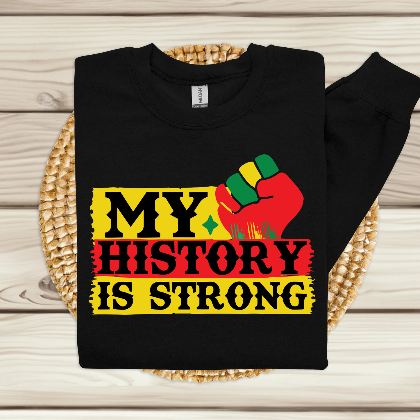 Black sweatshirt with 'My History is Strong' design on a woven mat