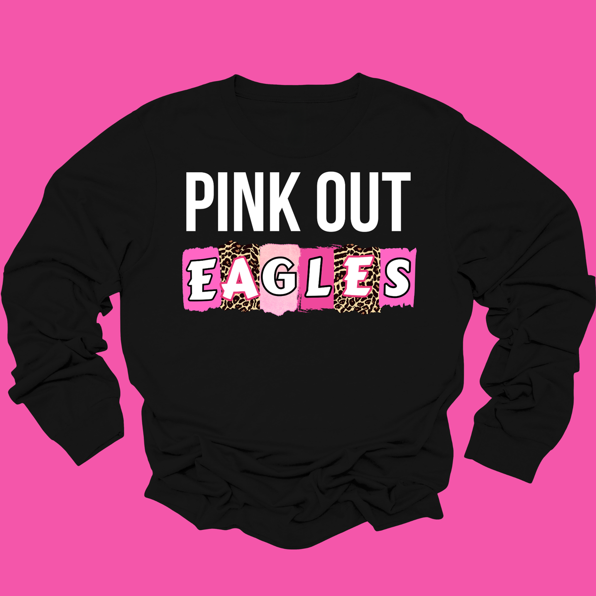 A black long-sleeve crewneck sweatshirt with a graphic print reading 'PINK OUT EAGLES' on the front, laid flat against a solid bright pink background.