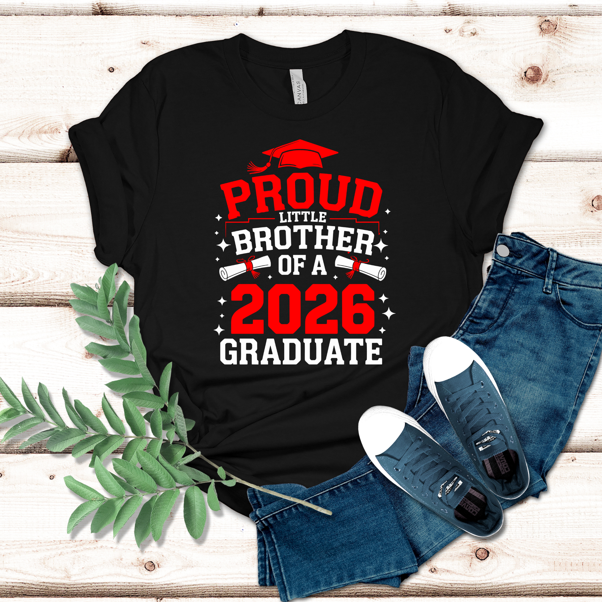Black t-shirt with 'Proud Little Brother of a 2026 Graduate' text on a wooden surface with jeans and shoes.