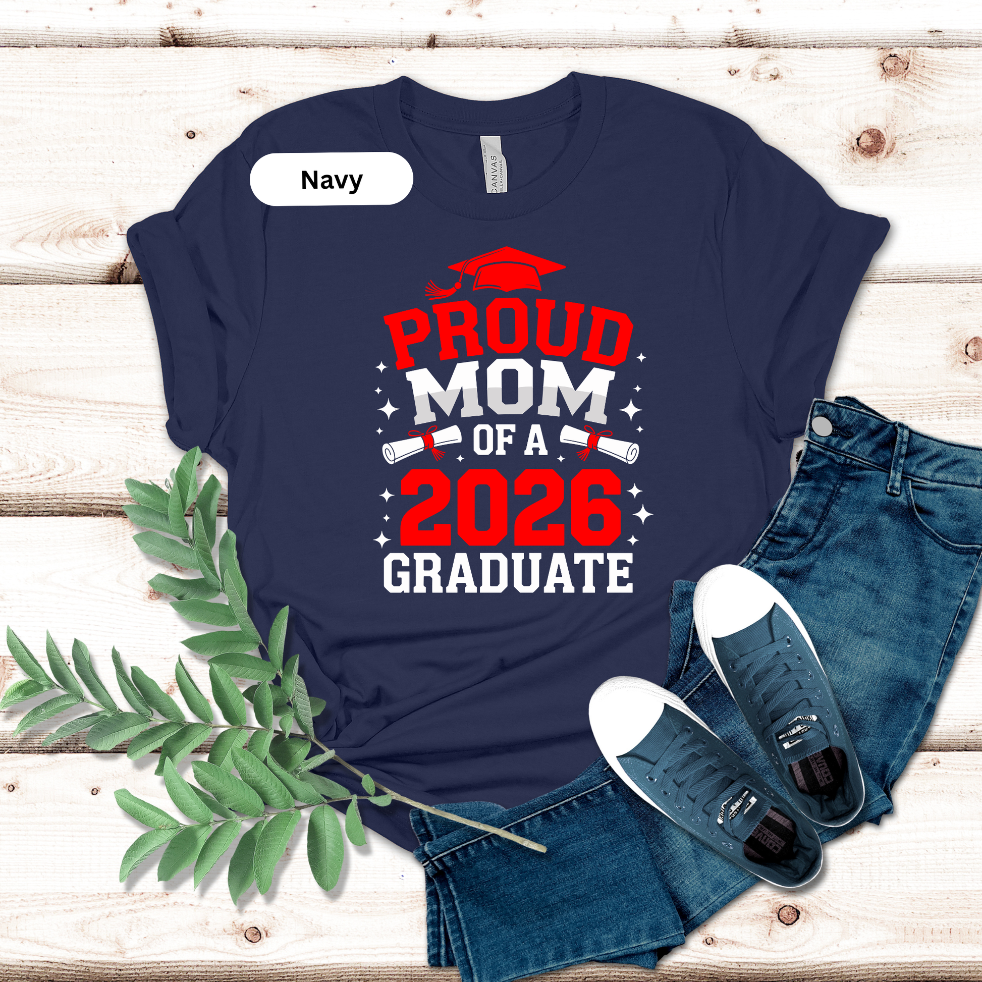 Navy t-shirt with 'Proud Mom of a 2026 Graduate' text on a wooden surface with jeans and shoes.