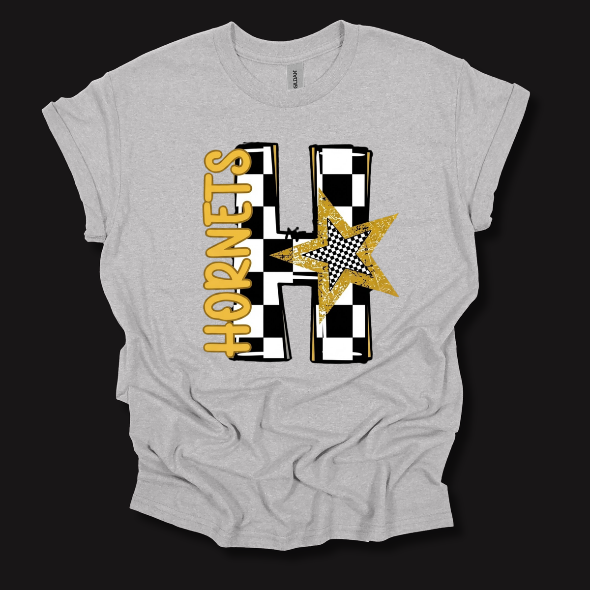 A light heather gray t-shirt with a graphic design featuring a large letter 'H' in a black and white checkered pattern, a gold glitter star, and the word 'HORNETS' in gold. The t-shirt is displayed flat against a solid black background.