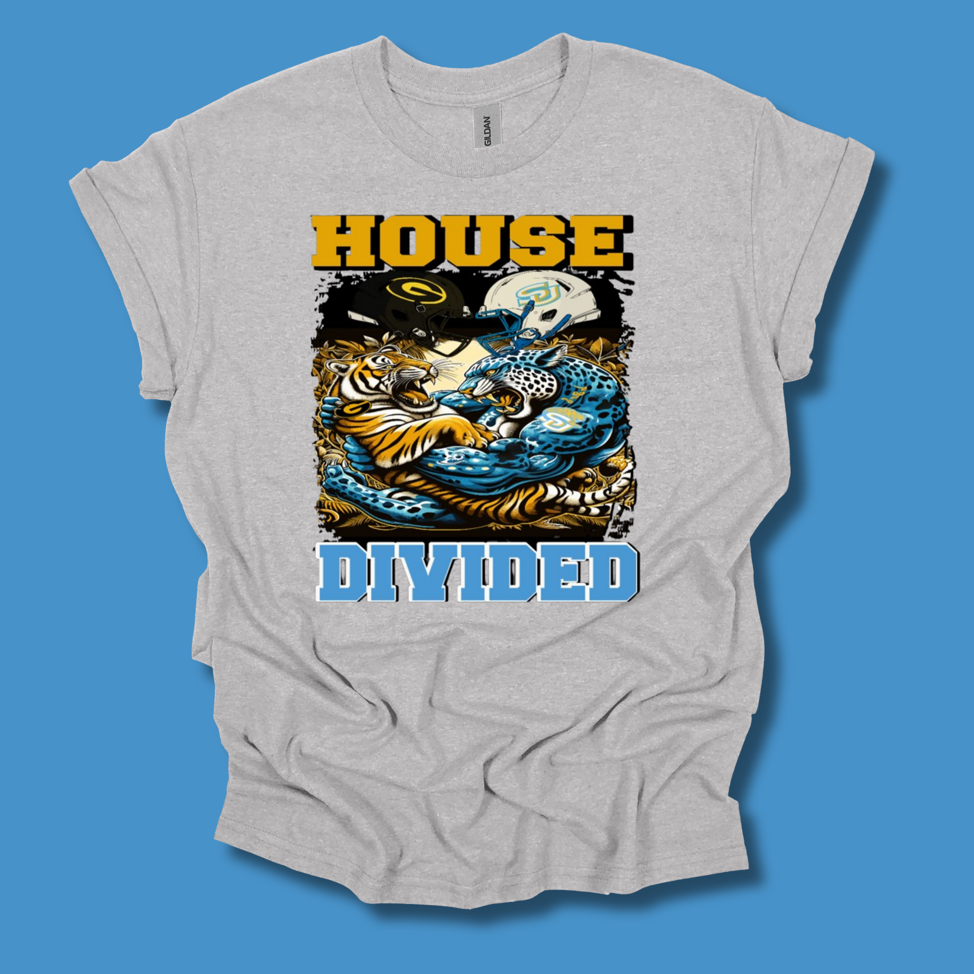 A light heather gray t-shirt with a graphic print featuring a tiger, a skull, and the text 'HOUSE DIVIDED' in yellow and blue, displayed against a solid blue background.