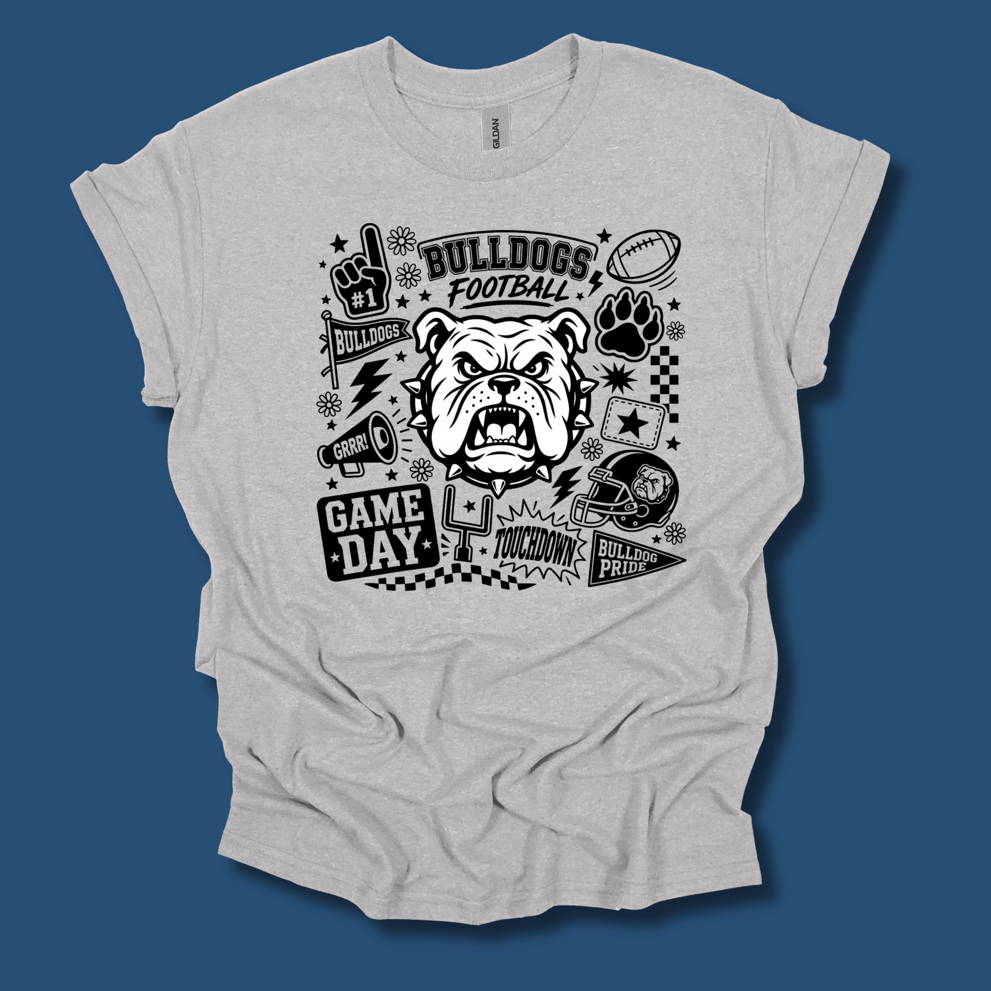 A light heather gray t-shirt with a black graphic print featuring a bulldog mascot and football-themed doodles, displayed against a solid dark blue background.