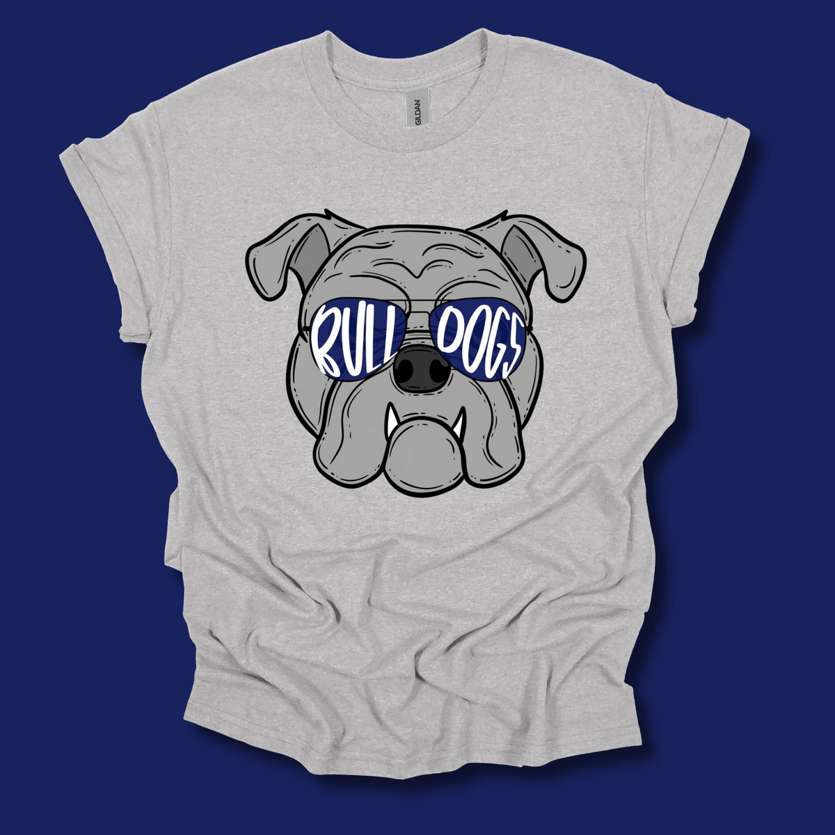A light heather gray t-shirt featuring a cartoon bulldog graphic wearing blue sunglasses with the text 'BULL DOGS' in white, displayed against a solid dark blue background.