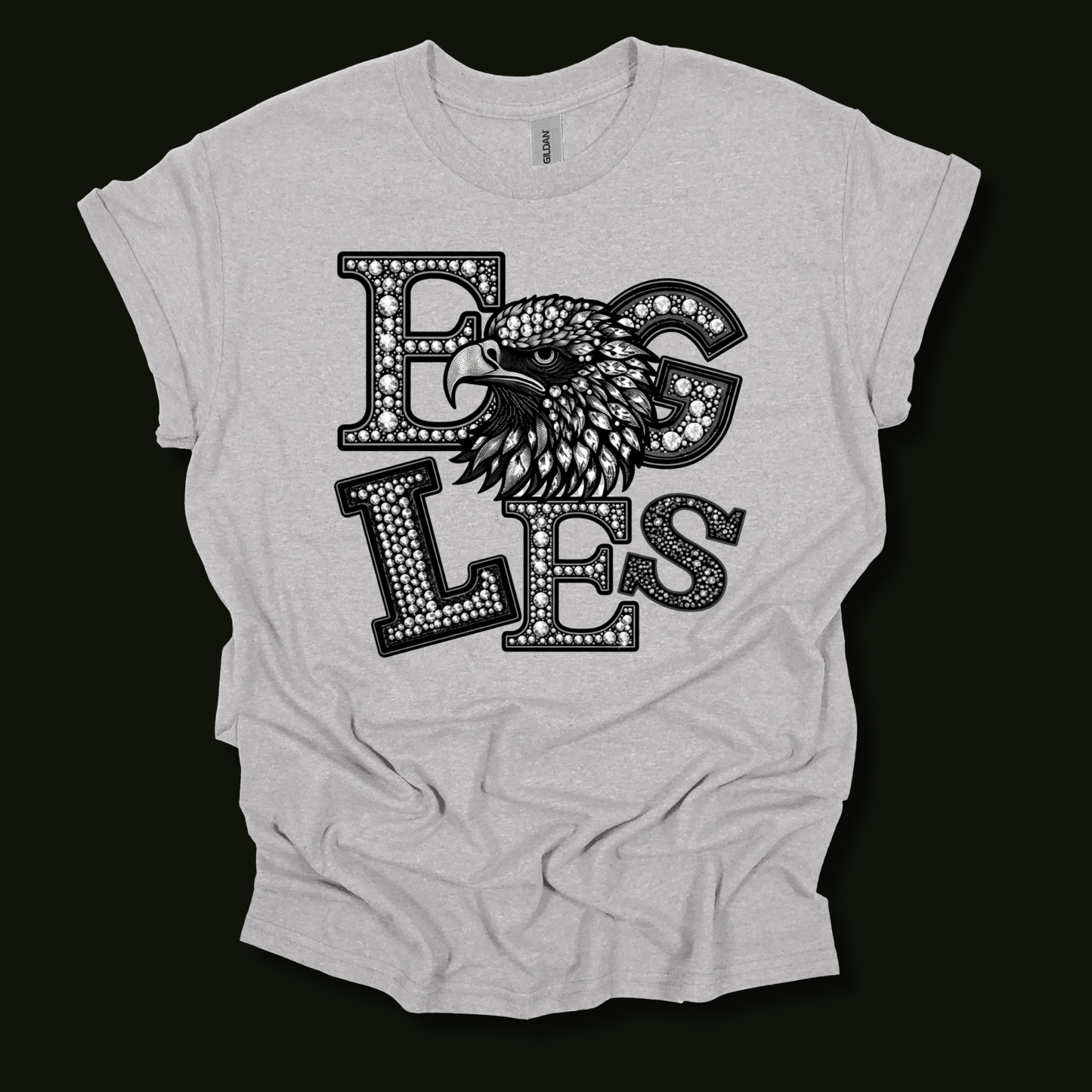 A light heather gray t-shirt with a black graphic print featuring the word 'EGLES' in a dotted, textured font and an eagle's head integrated into the design, displayed on a solid black background.