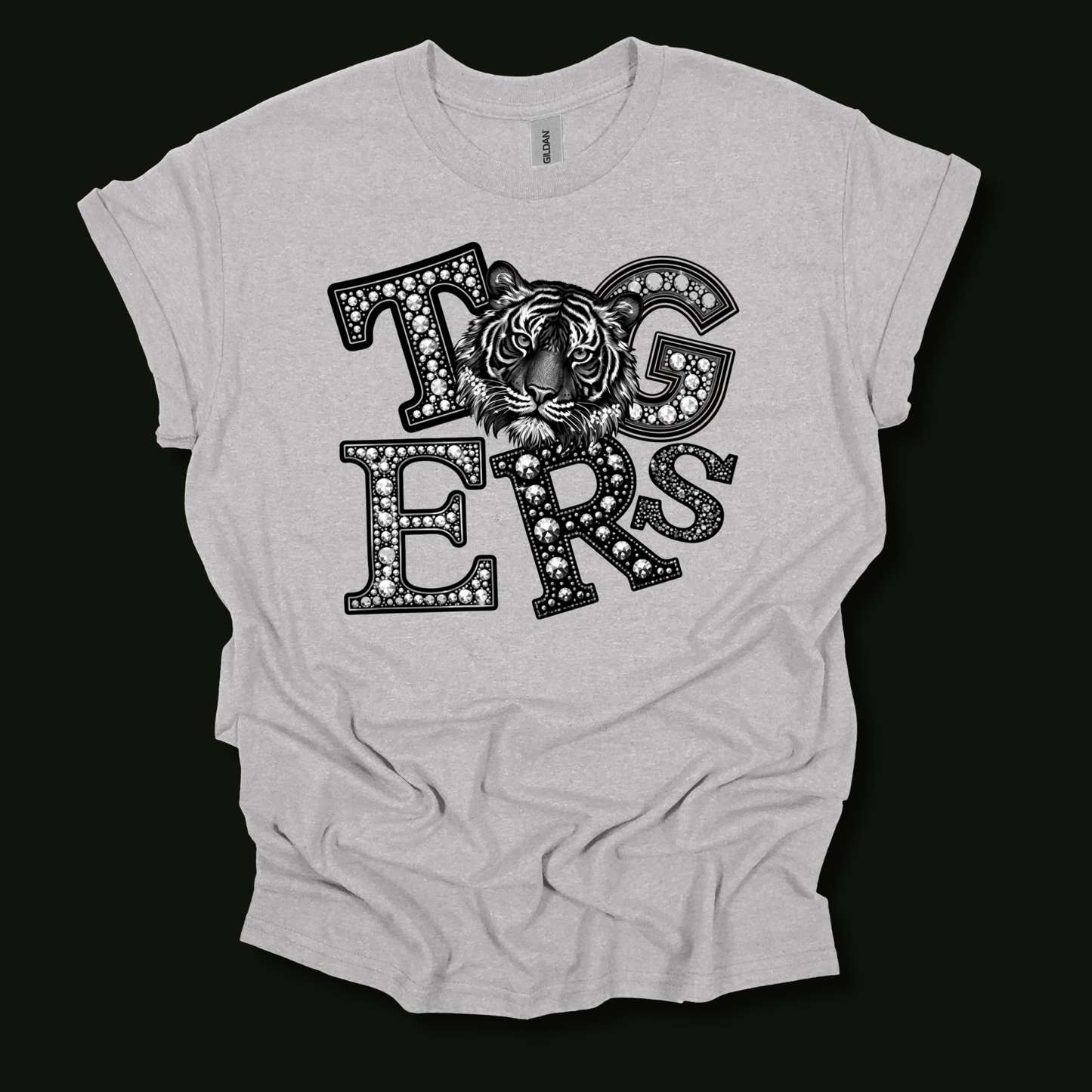 A light gray heather t-shirt with a black graphic print spelling 'Tigers' in a patterned font, featuring a tiger face in the center, laid flat against a black background.