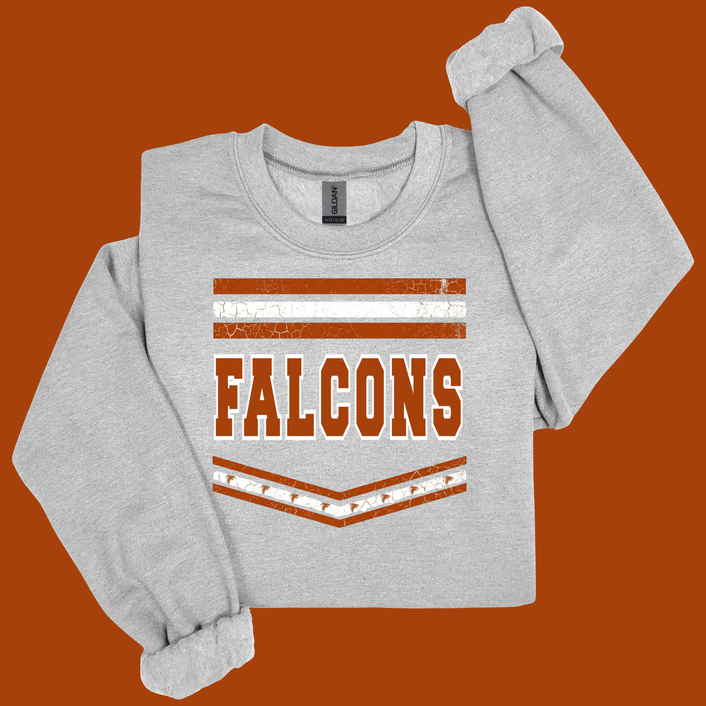 A light heather gray long-sleeve sweatshirt with a distressed orange and white graphic that reads 'FALCONS' on the front, displayed against a solid orange background.