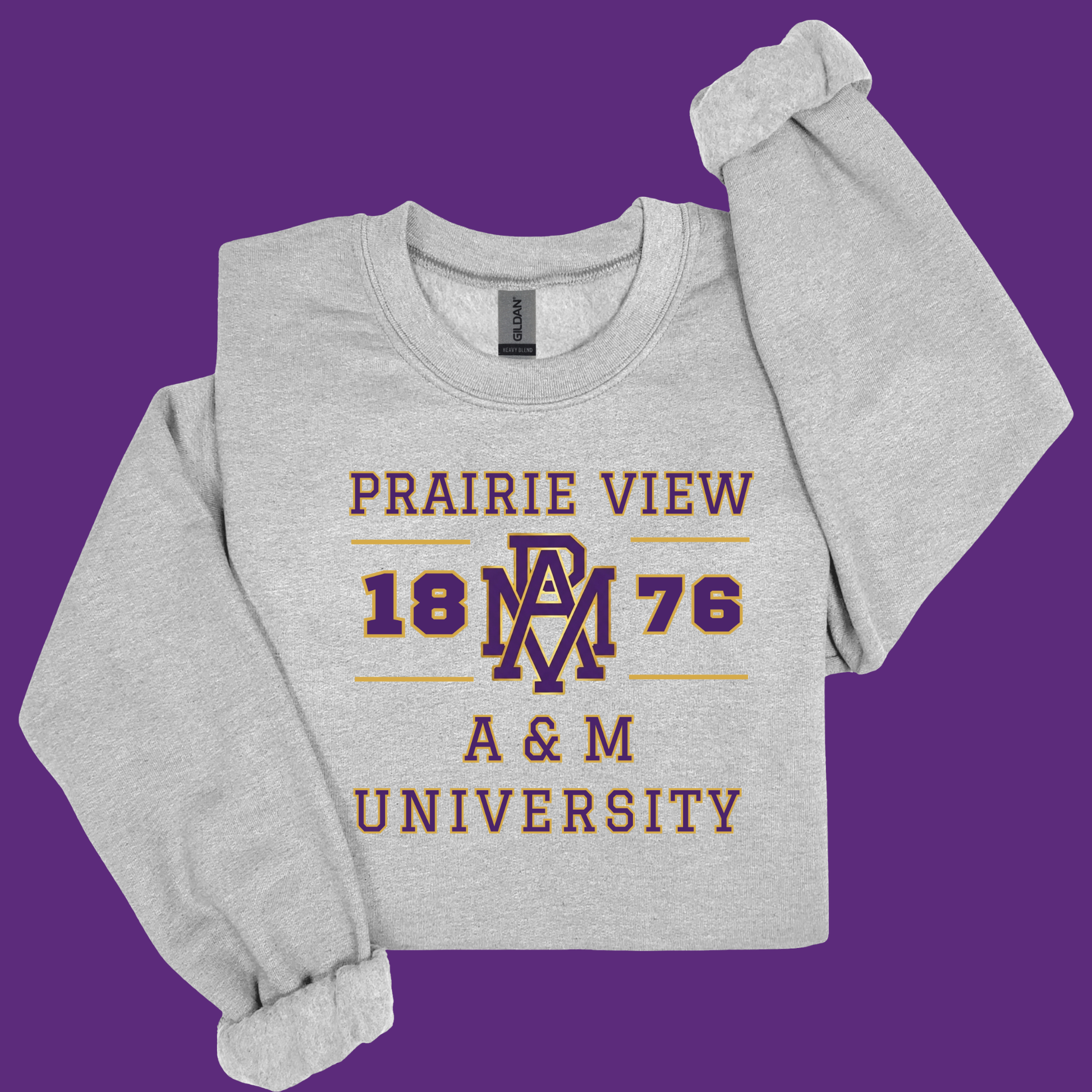 A light heather gray long-sleeve sweatshirt featuring a maroon and gold graphic print that reads 'PRAIRIE VIEW 1876 A & M UNIVERSITY' with a central 'PRAIRIE VIEW' monogram, laid flat against a solid purple background.