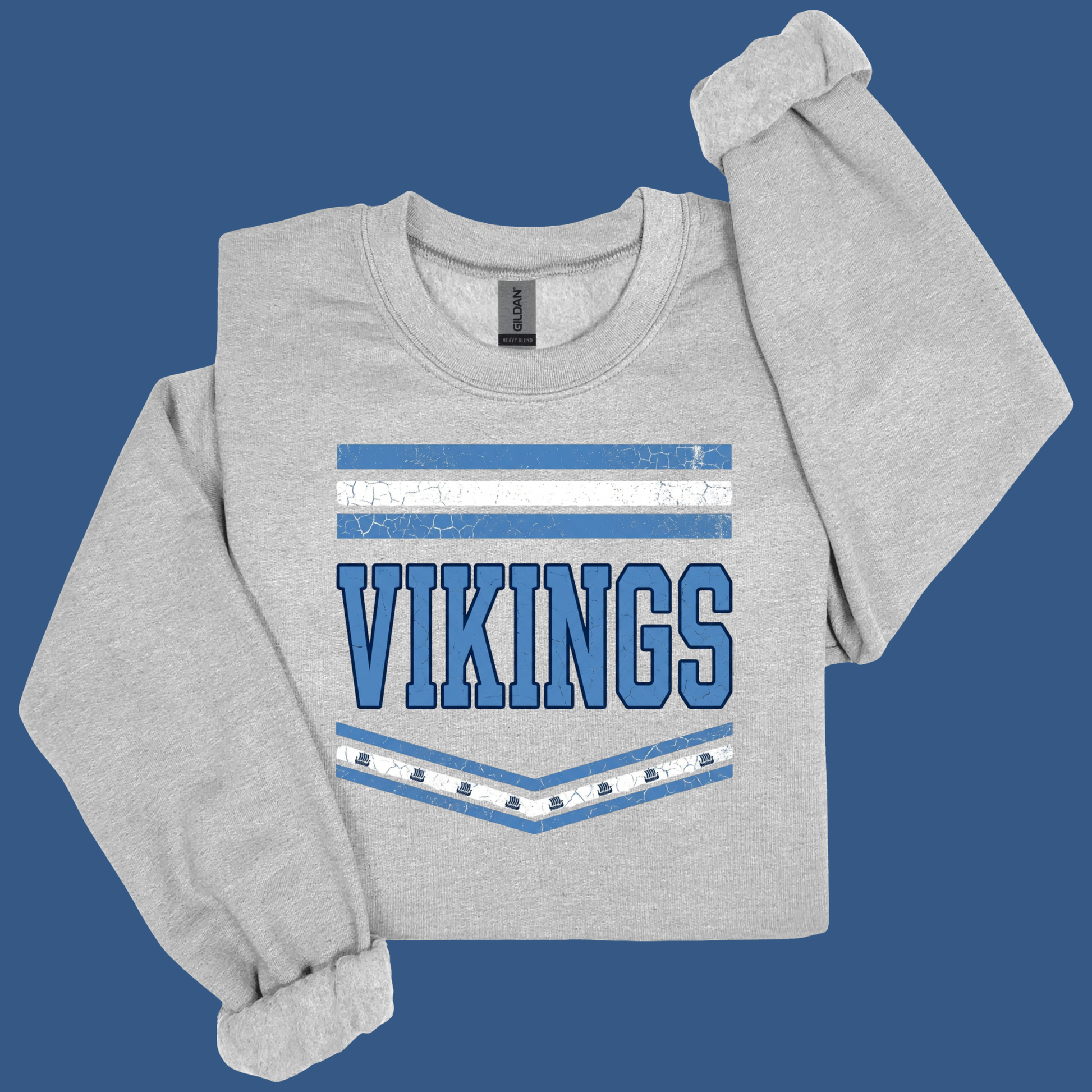 A light heather gray long-sleeve sweatshirt with a blue and white Vikings graphic on the front, displayed on a solid blue background.