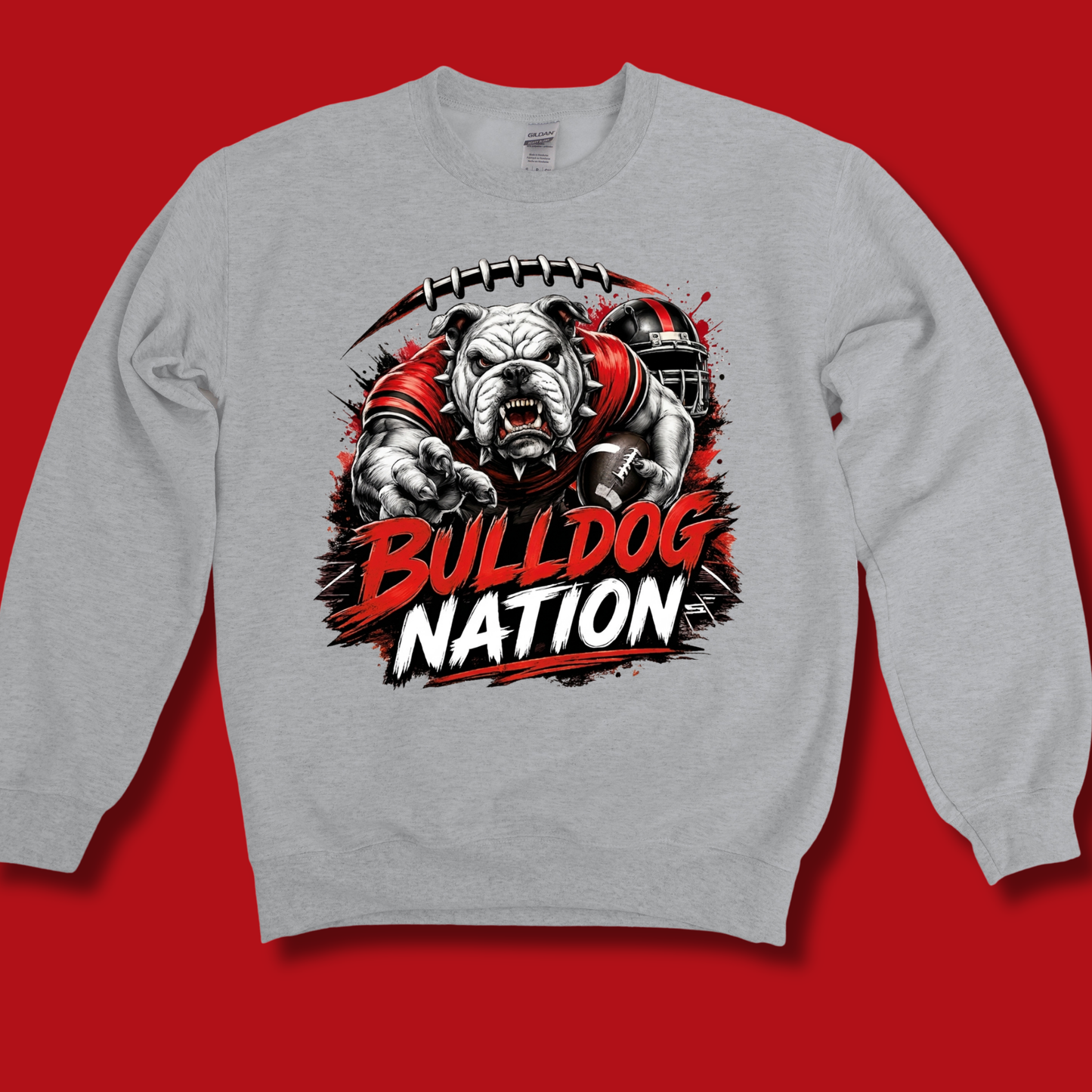 A light gray crewneck sweatshirt featuring a large graphic print of a bulldog football player with the text 'BULLDOG NATION' in red and white, displayed against a solid red background.