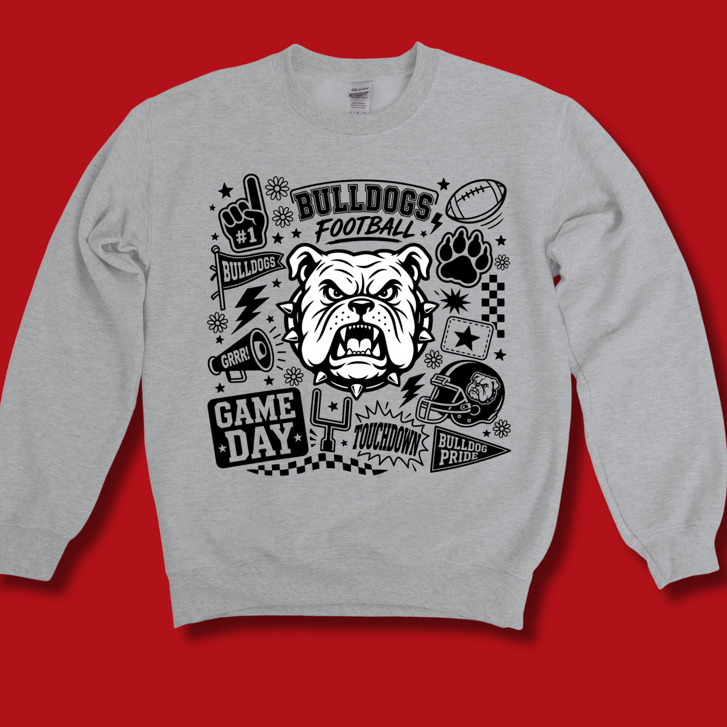 A light gray crewneck sweatshirt with a black graphic print featuring a bulldog mascot, football, paw print, and 'BULLDOGS FOOTBALL' text, displayed against a solid red background.