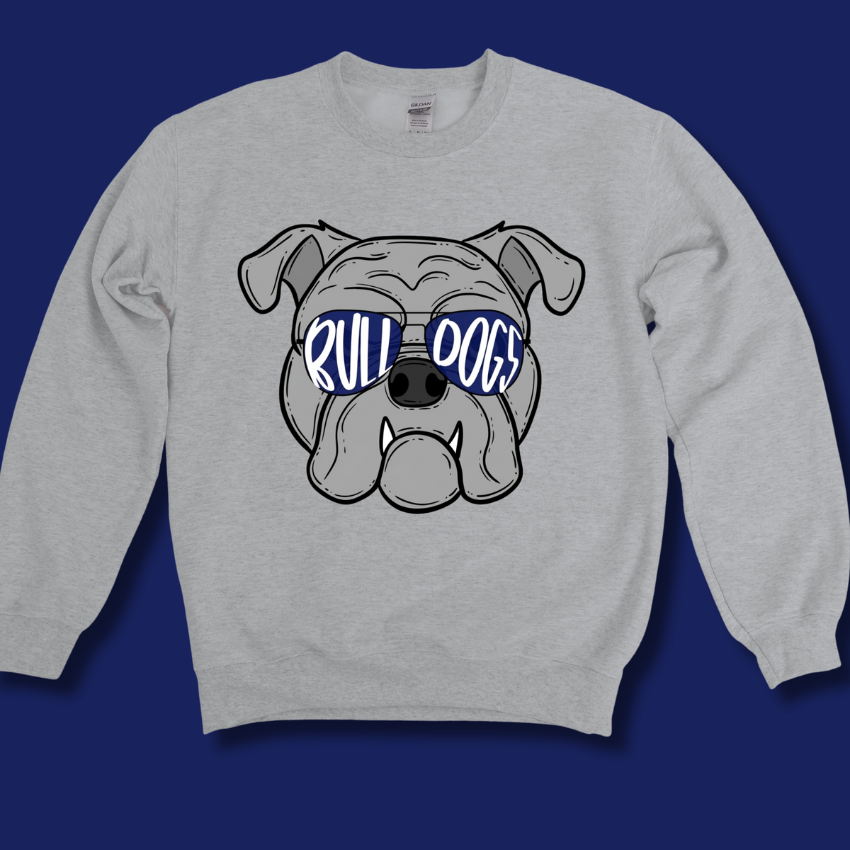 A light heather gray crewneck sweatshirt featuring a cartoon bulldog graphic wearing blue sunglasses with the text 'RULL DOGS' in white, displayed against a solid dark blue background.