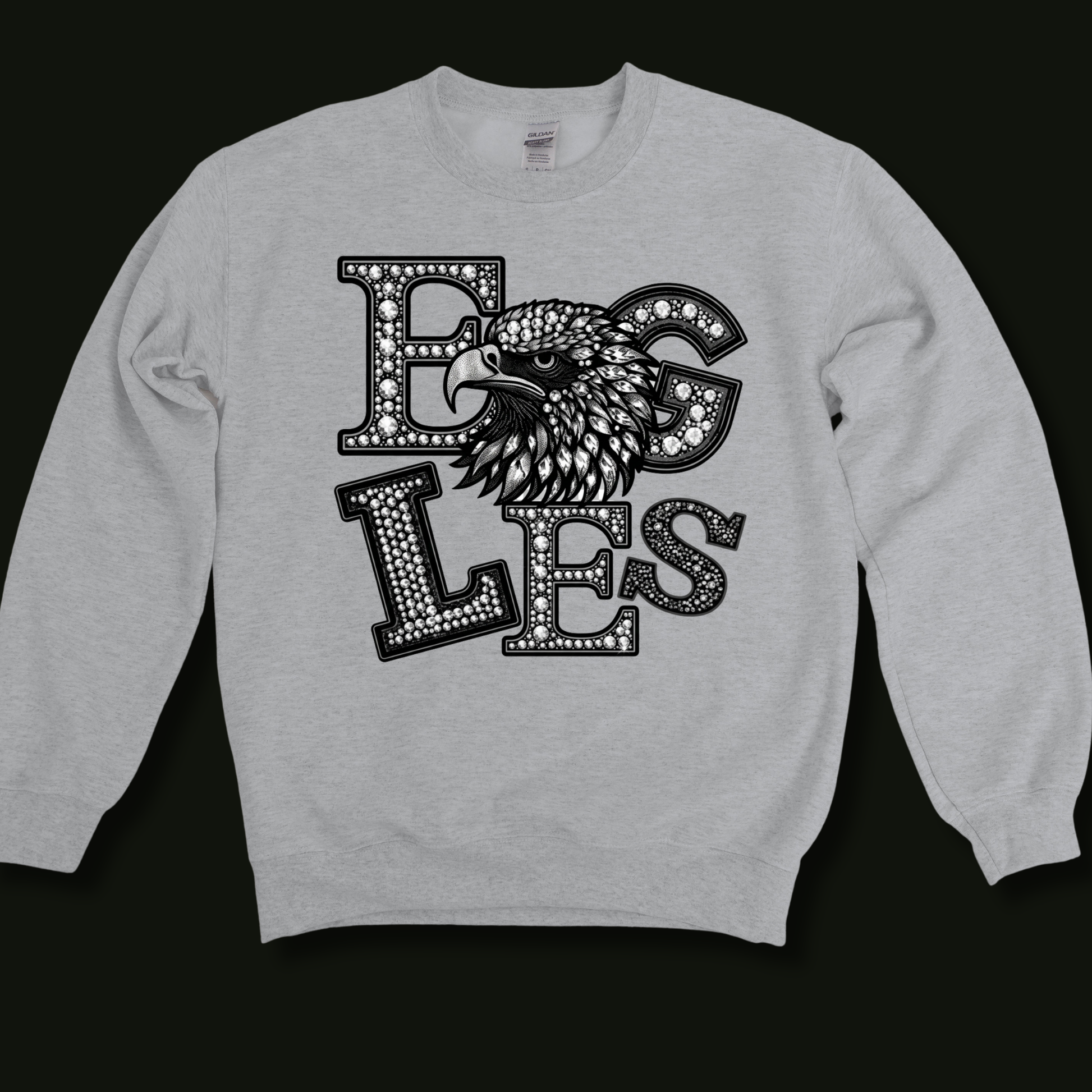 A light heather gray crewneck sweatshirt featuring a large black graphic on the front with the word 'EGLES' in a dotted outline font and an eagle head illustration, shown against a solid black background.