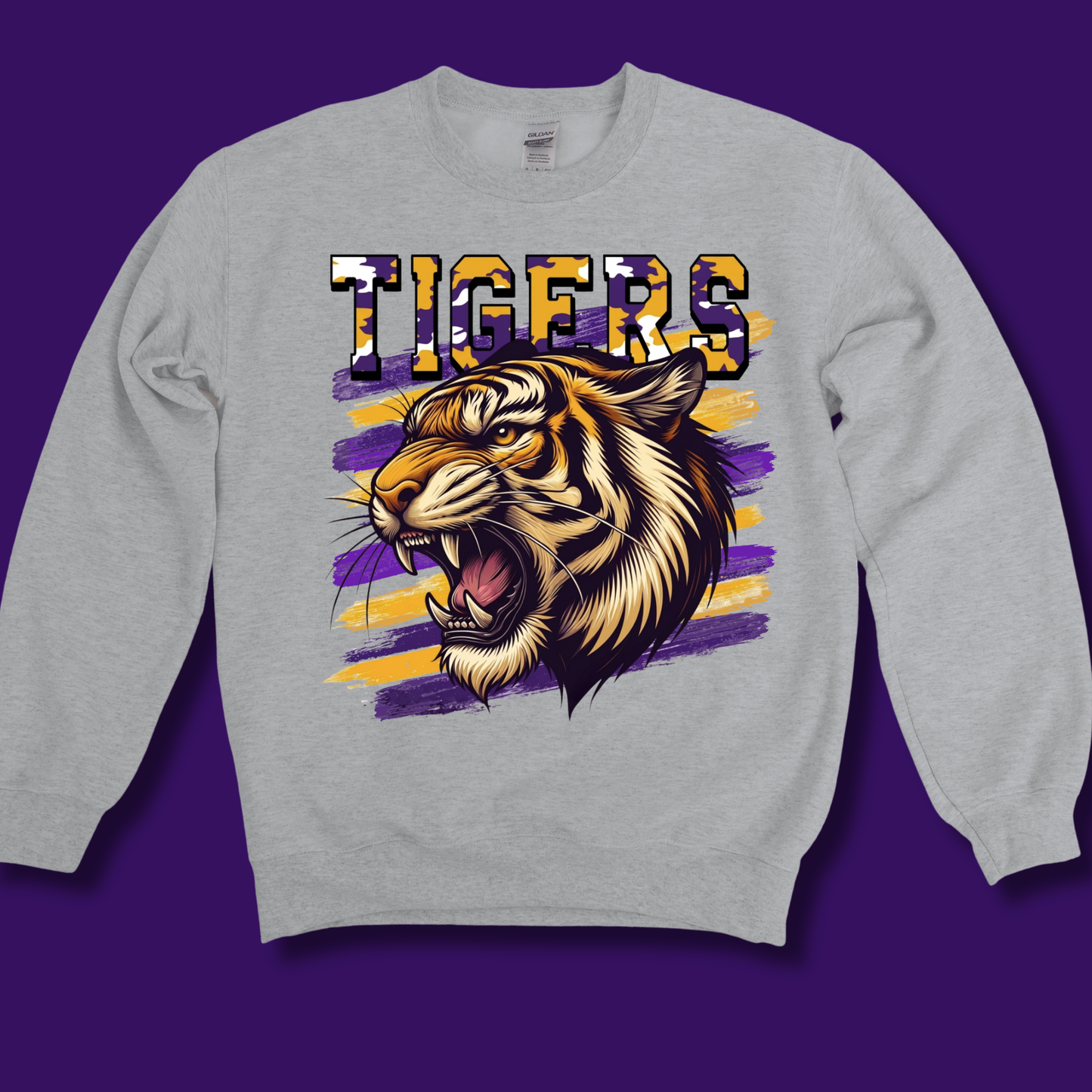 A light gray crewneck sweatshirt featuring a graphic print of a roaring tiger and the word 'TIGERS' in a bold, patterned font, set against a solid purple background.