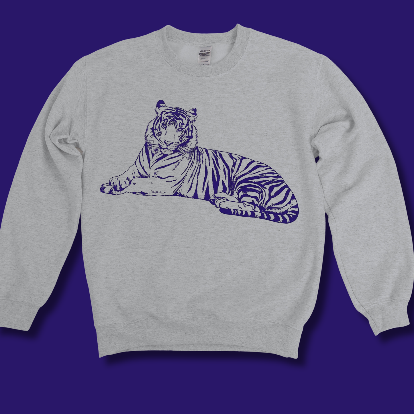 A light heather gray crewneck sweatshirt featuring a dark purple line art graphic of a lying tiger on the chest, displayed against a solid dark purple background.