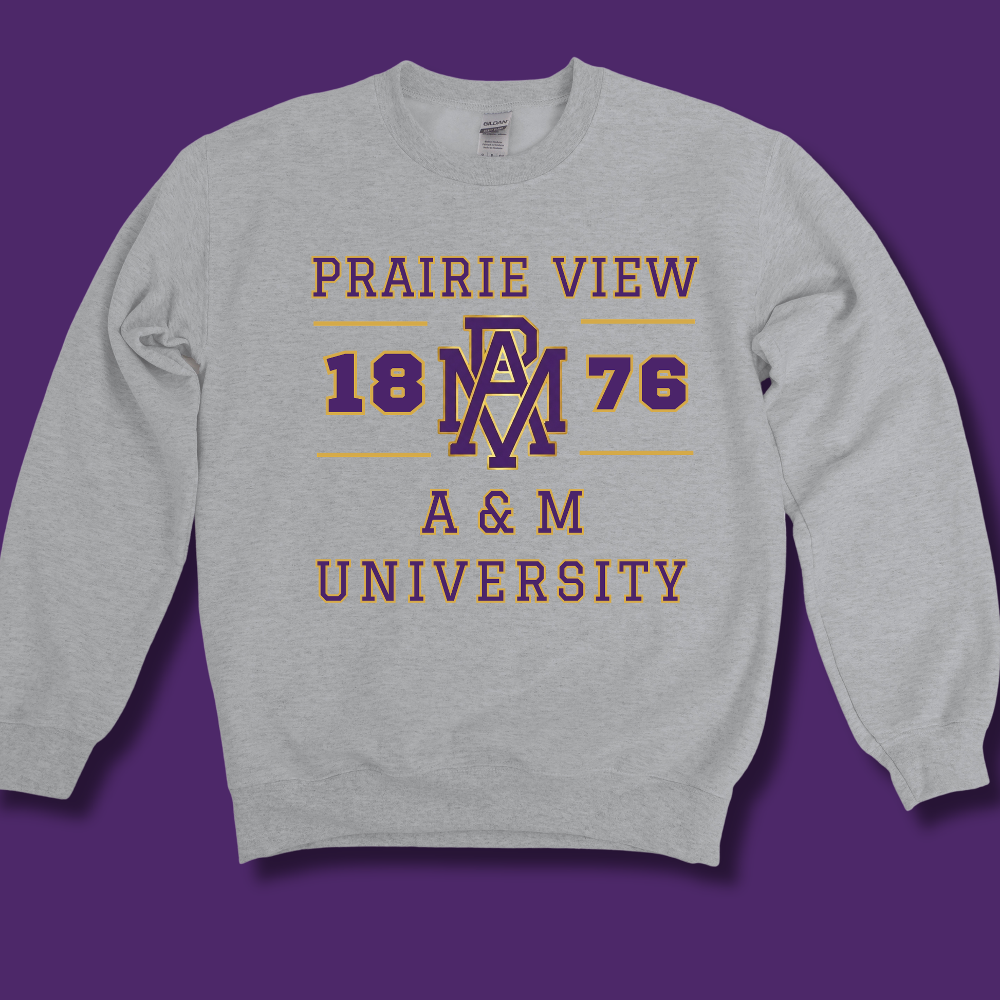 A light heather gray crewneck sweatshirt featuring a purple and maroon graphic print that reads 'PRAIRIE VIEW 1876 A & M UNIVERSITY' with an interlocking 'AM' logo, displayed against a solid purple background.