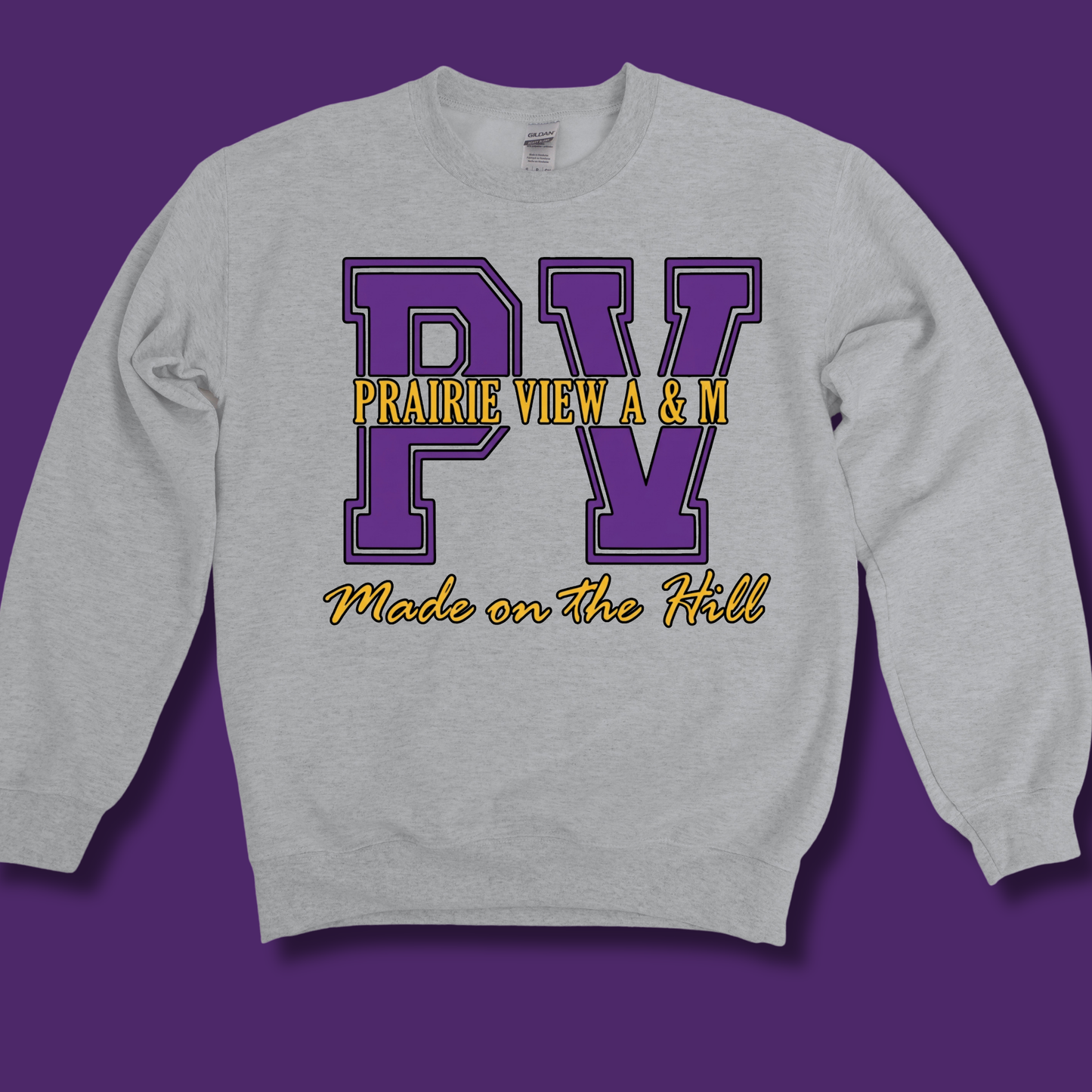 A light heather gray crewneck sweatshirt with a purple and yellow graphic on the front reading 'PV PRAIRIE VIEW A & M Made on the Hill', shown against a solid purple background.