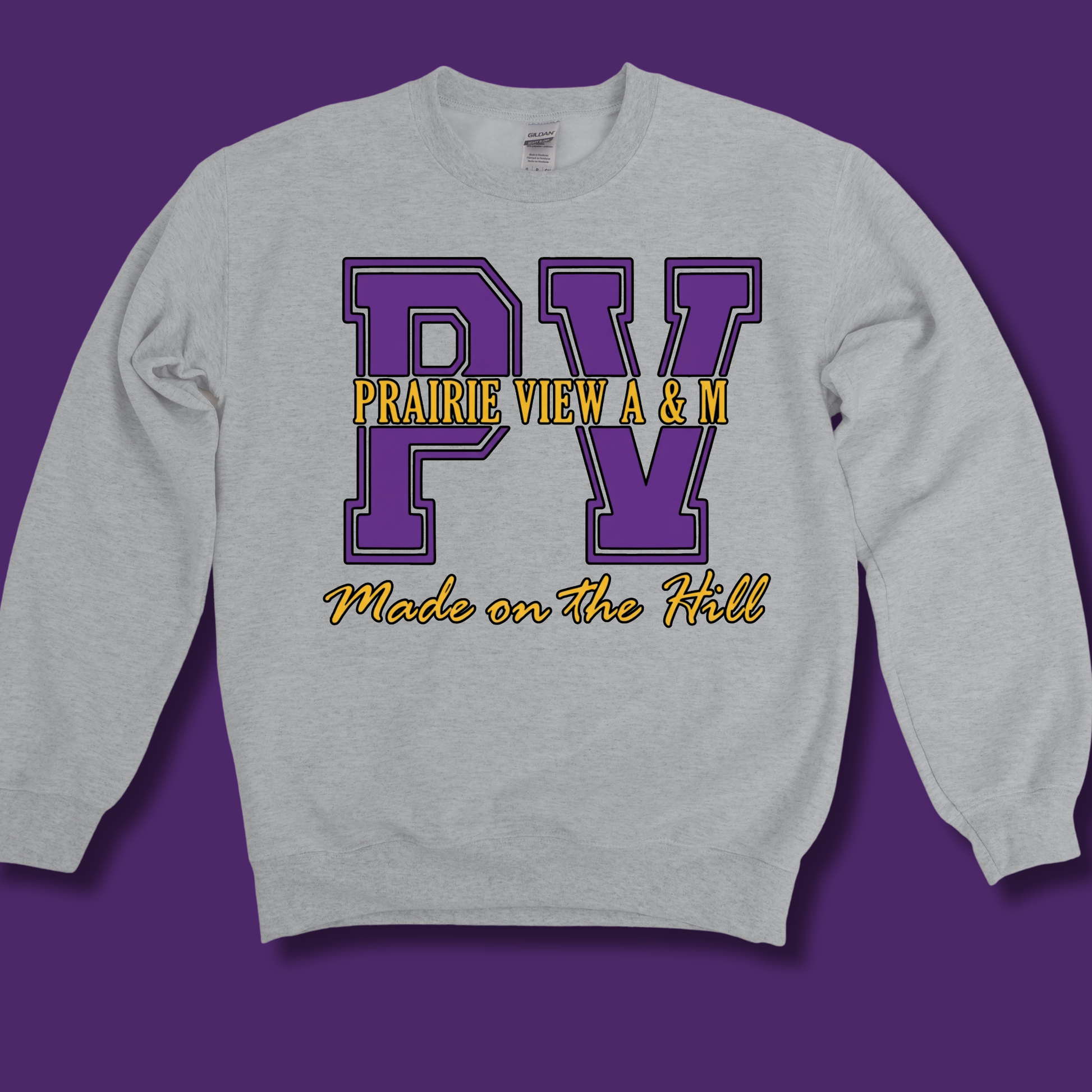 A light heather gray crewneck sweatshirt with a purple and yellow graphic on the front reading 'PV PRAIRIE VIEW A & M Made on the Hill', shown against a solid purple background.