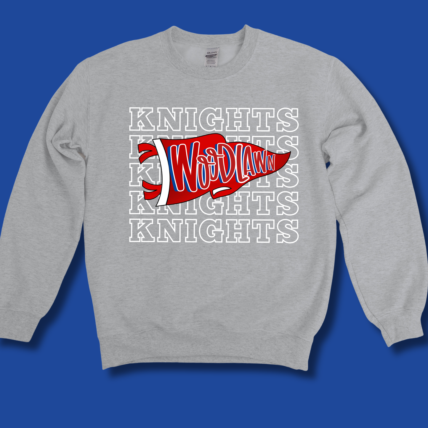 A light gray crewneck sweatshirt featuring a red and white 'Woodlawn' pennant graphic with 'KNIGHTS' text behind it, displayed against a solid blue background.