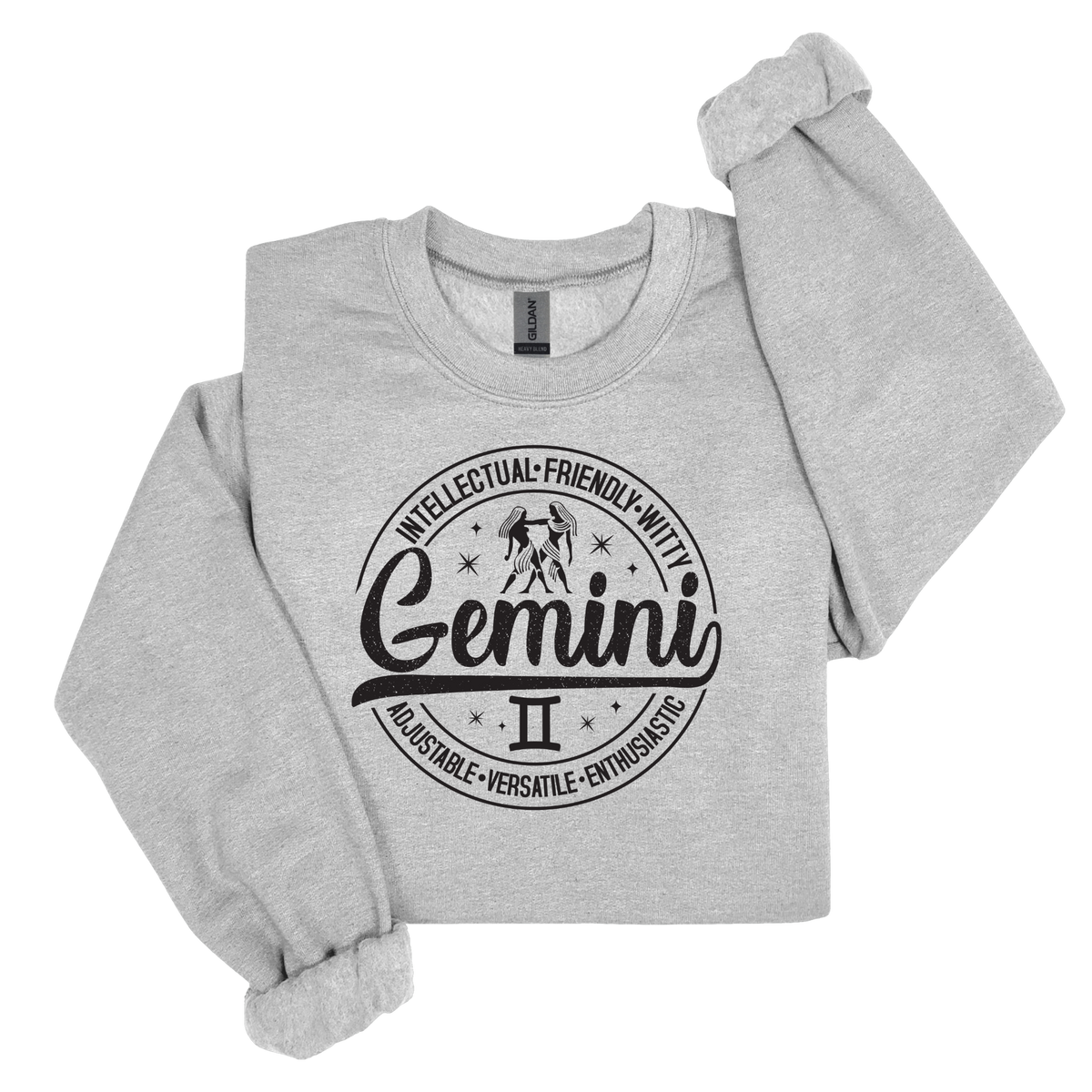 Grey crewneck t-shirt laid flat, featuring a circular white Gemini zodiac graphic with the twins illustration, the word "Gemini," and trait keywords like intellectual, friendly, witty, enthusiastic, versatile, and adjustable.