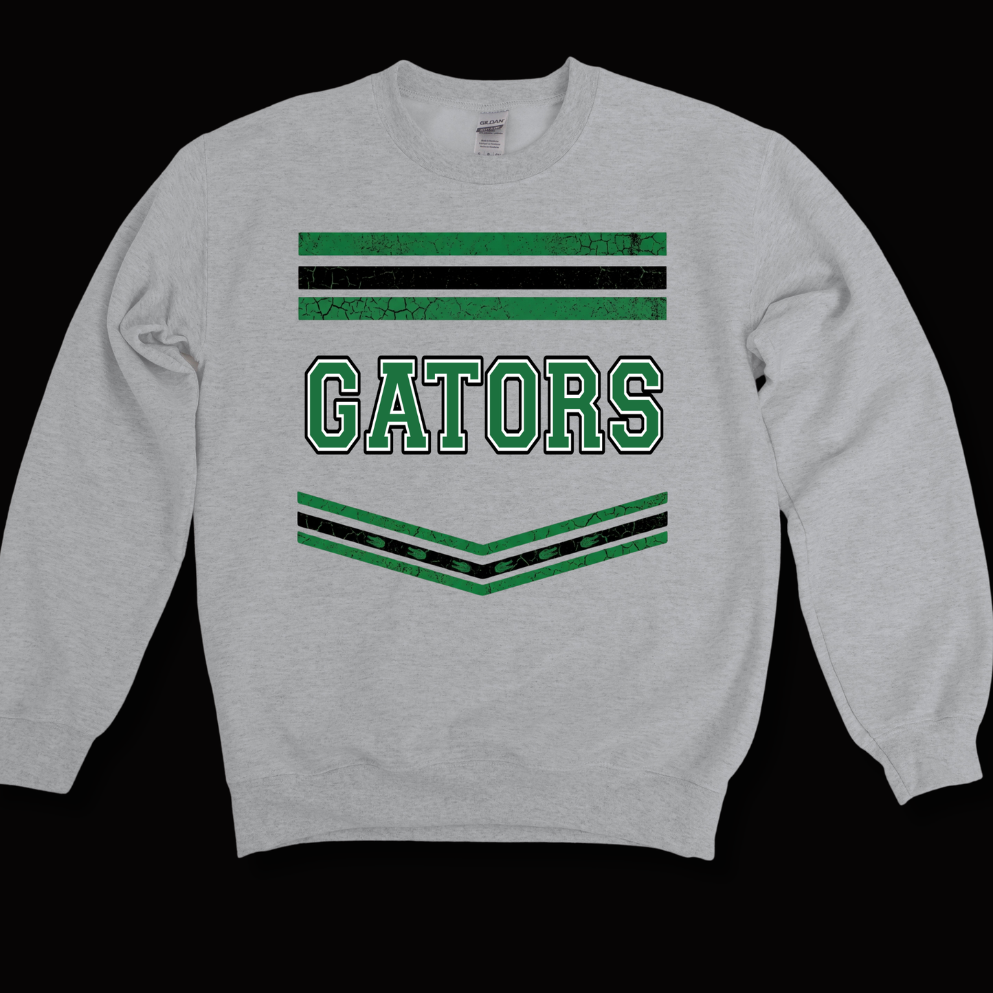 A light heather gray crewneck sweatshirt featuring a distressed green and black graphic design on the chest with the word 'GATORS' in green varsity-style lettering, set against a solid black background.