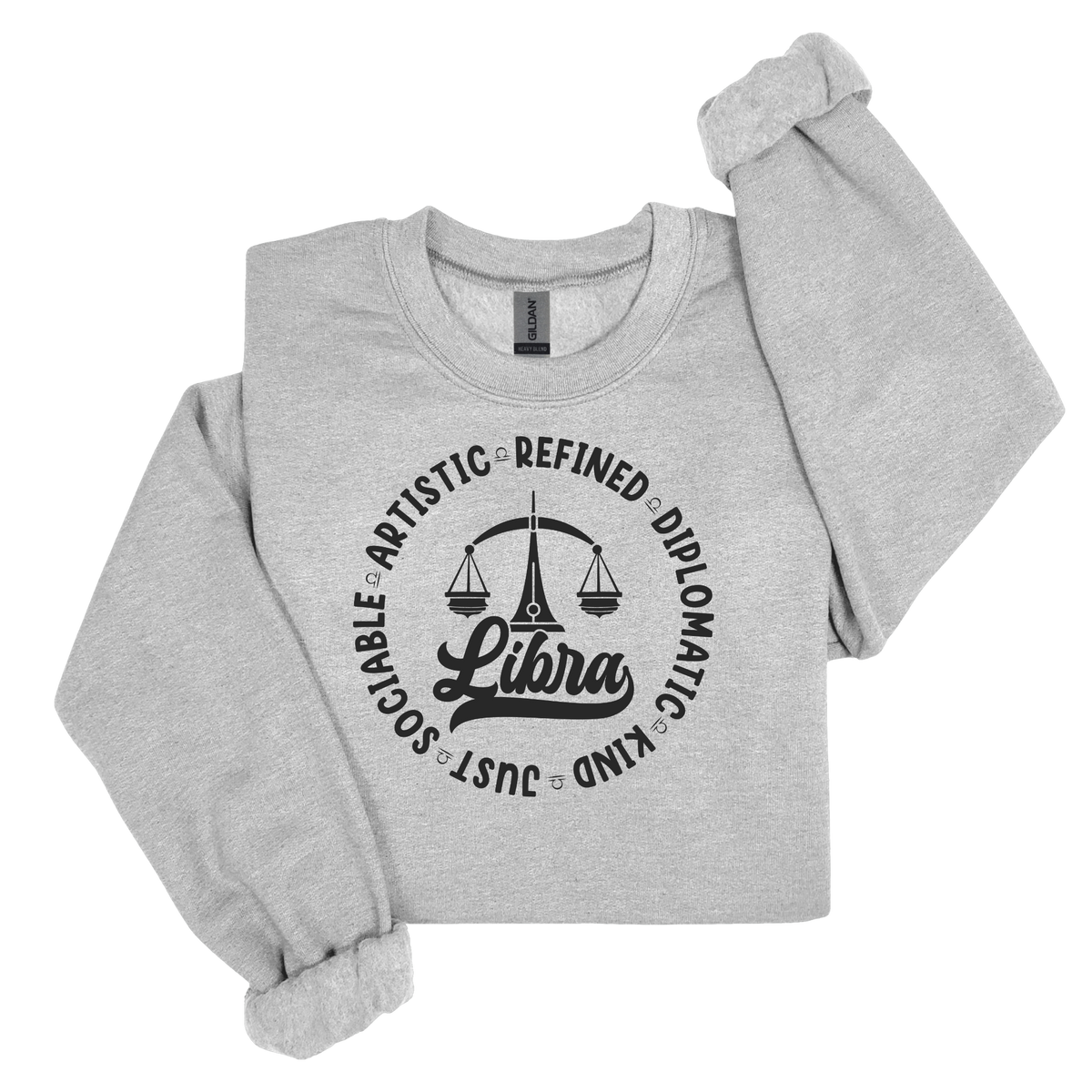 Woman wearing a white crewneck t-shirt featuring a black circular Libra zodiac graphic with a scales illustration, the word "Libra," and trait keywords like artistic, refined, diplomatic, kind, just, and sociable.