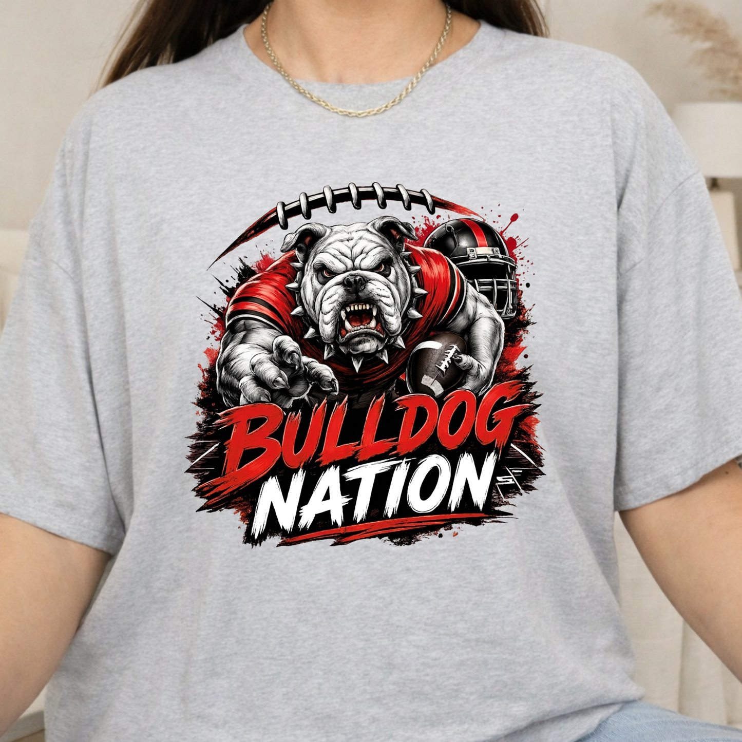 A person wearing a light heather gray t-shirt with a large graphic print of a bulldog football player and the text 'BULLDOG NATION' in red and white.