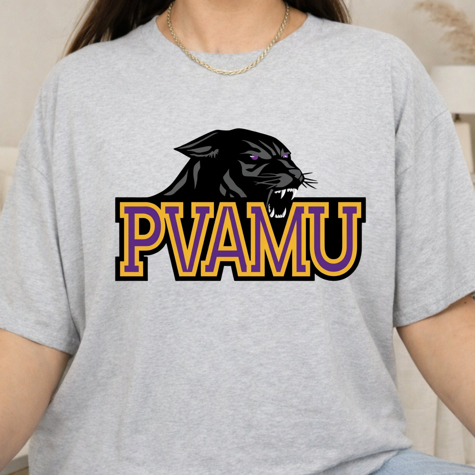 A person wearing a light heather gray t-shirt with a graphic of a black panther and the text 'PVAMU' in purple and gold outlined letters.