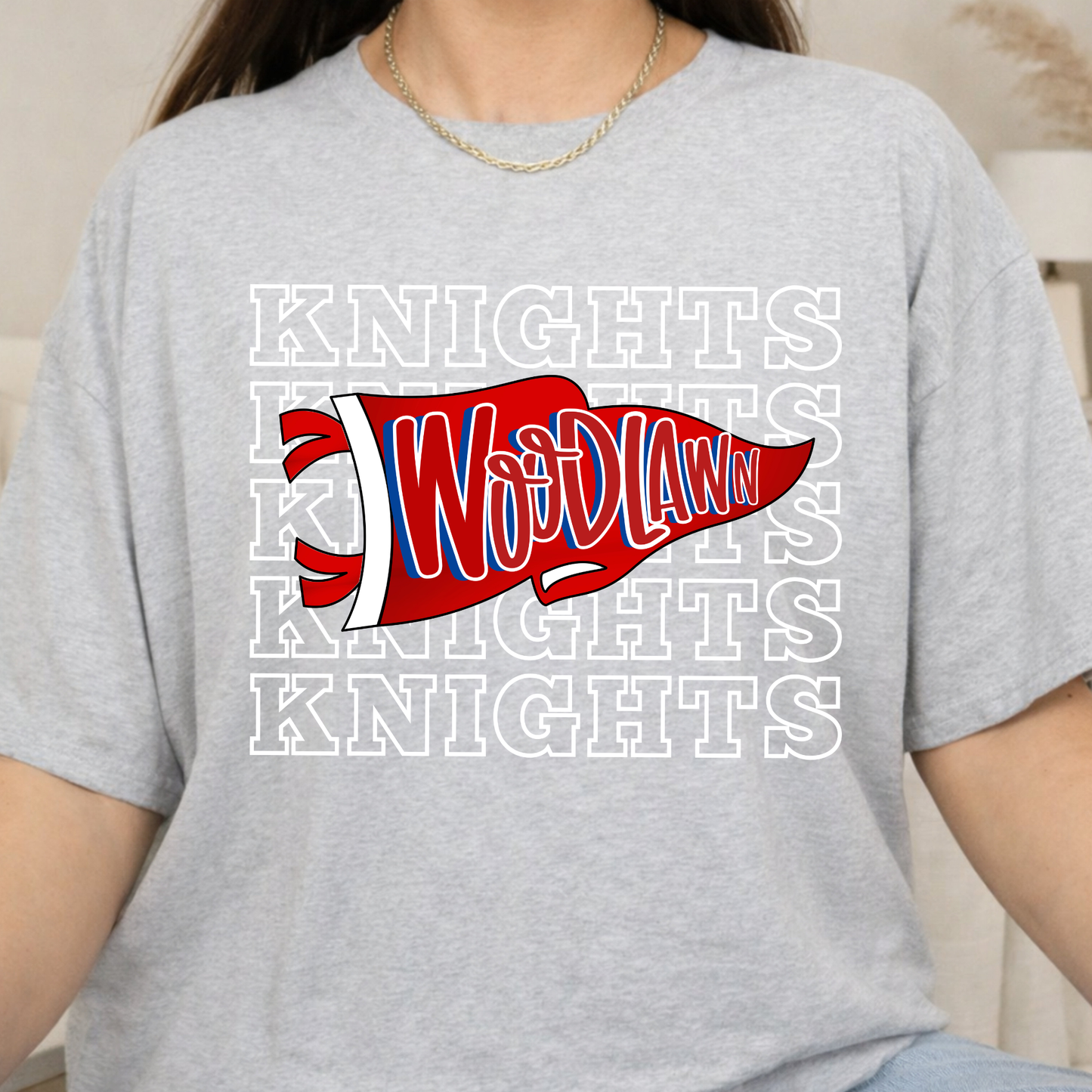 A person wearing a light heather gray t-shirt with a red, white, and blue 'WoD Law' pennant graphic over a repeating white 'KNIGHTS' background.