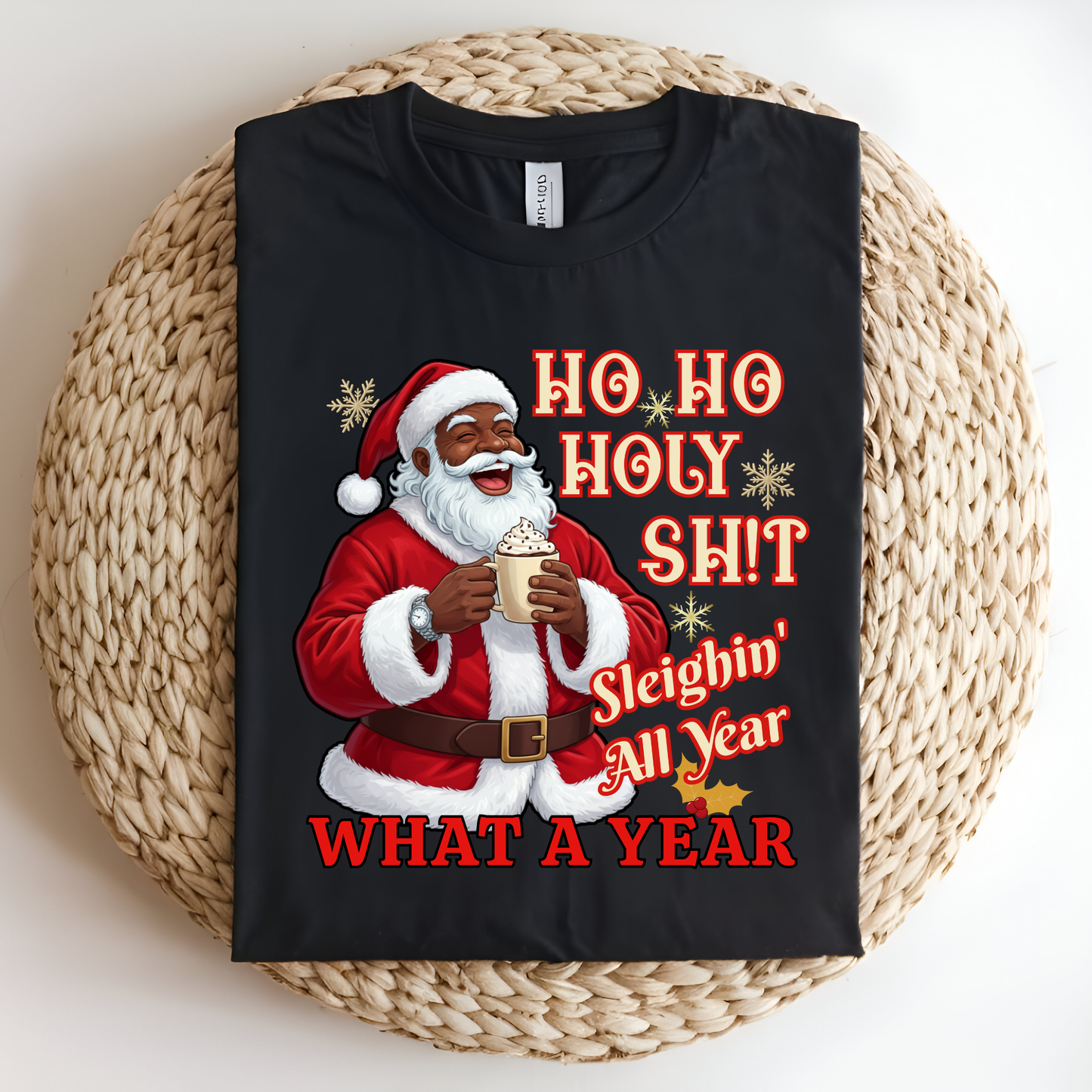 Black t-shirt with a graphic of Santa Claus holding a cup, text 'HO HO HOLY SHIT Sleighin' All Year WHAT A YEAR', on a woven mat.