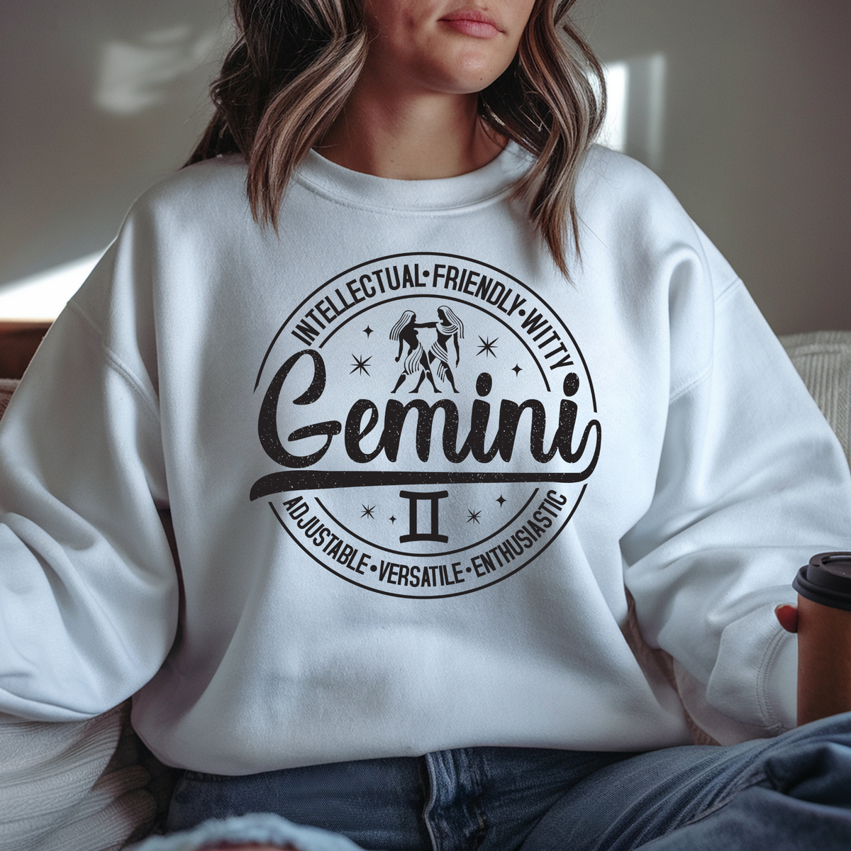white sweater  laid flat, featuring a circular white Gemini zodiac graphic with the twins illustration, the word "Gemini," and trait keywords like intellectual, friendly, witty, enthusiastic, versatile, and adjustable.