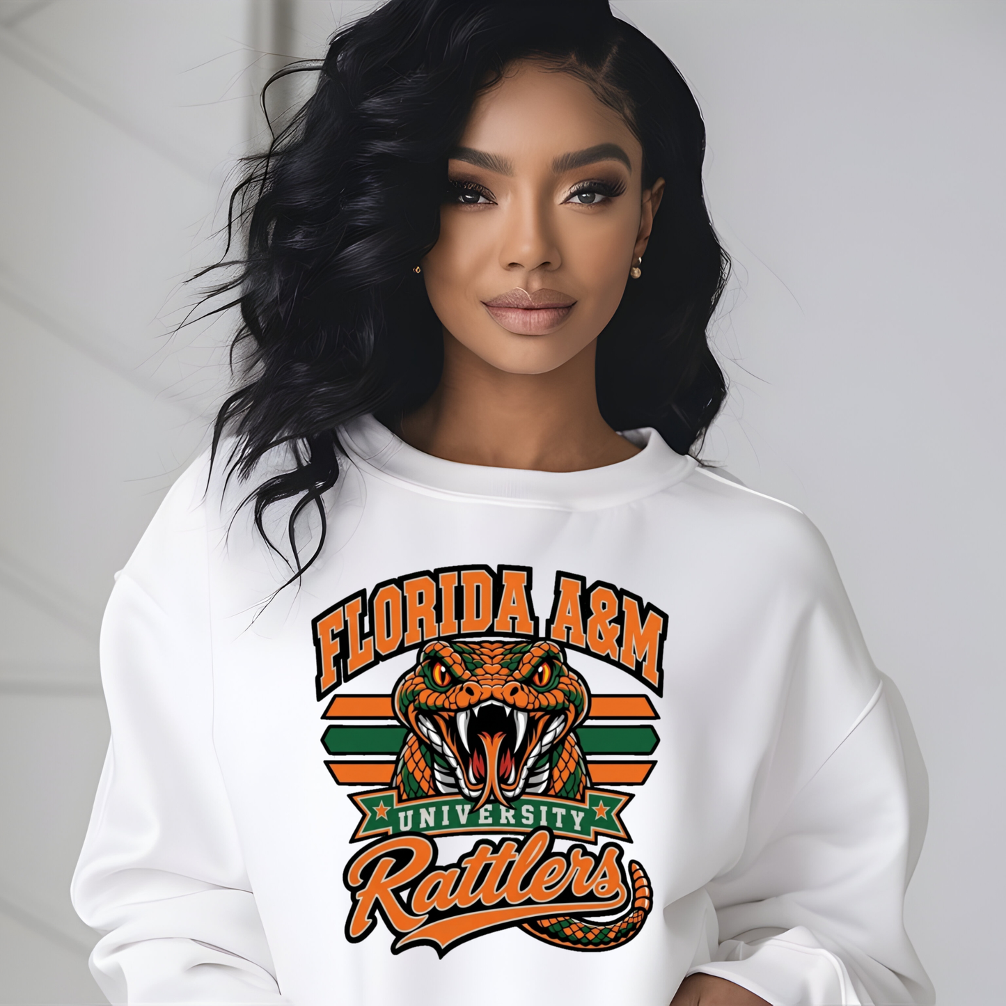 A woman wearing a white crewneck sweatshirt with a large Florida A&M University Rattlers graphic on the front, featuring an orange and black rattlesnake and green and orange stripes.