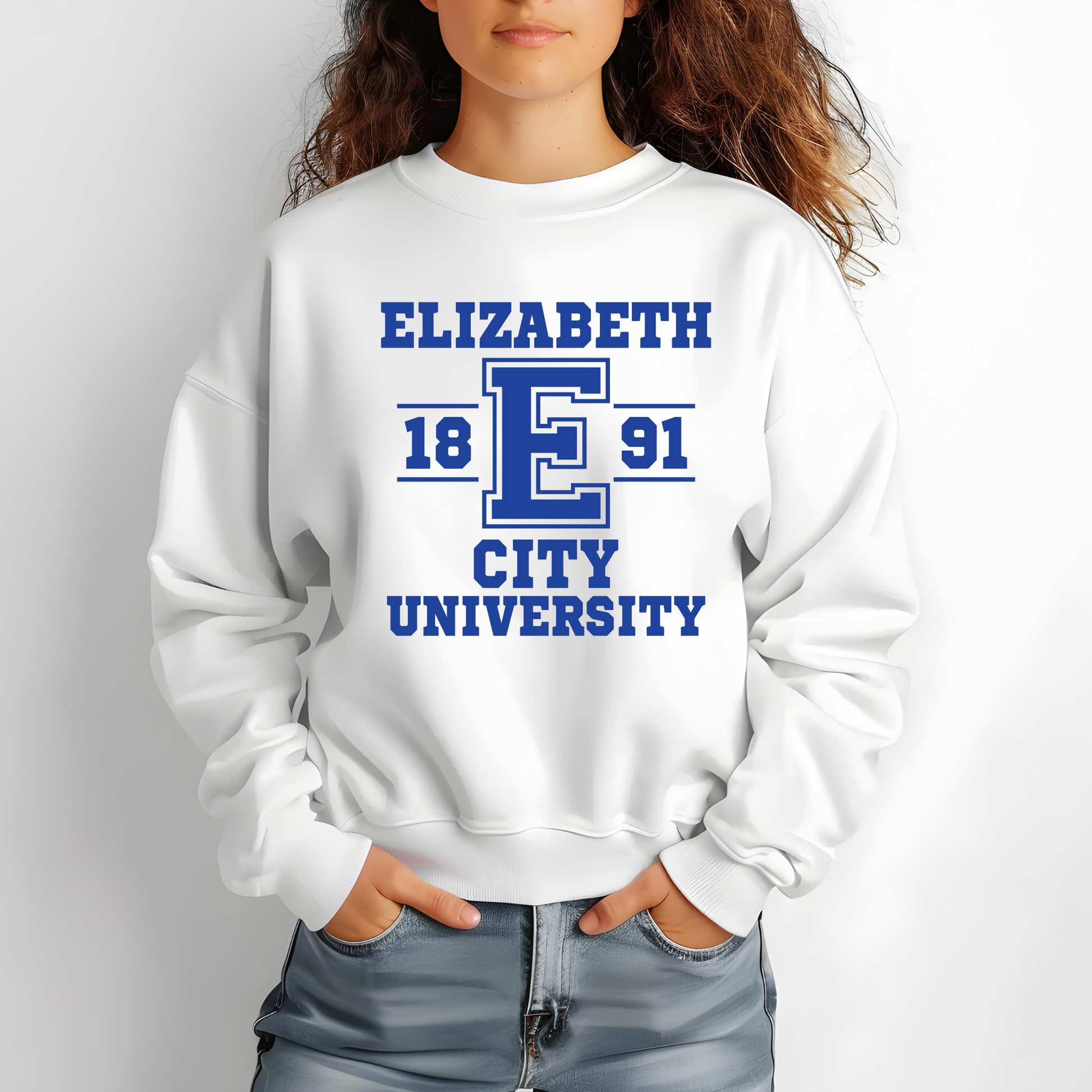 A woman wearing a white crewneck sweatshirt with a blue collegiate-style graphic that reads 'ELIZABETH 1891 CITY UNIVERSITY' around a large letter E, paired with light blue jeans against a plain light gray background.