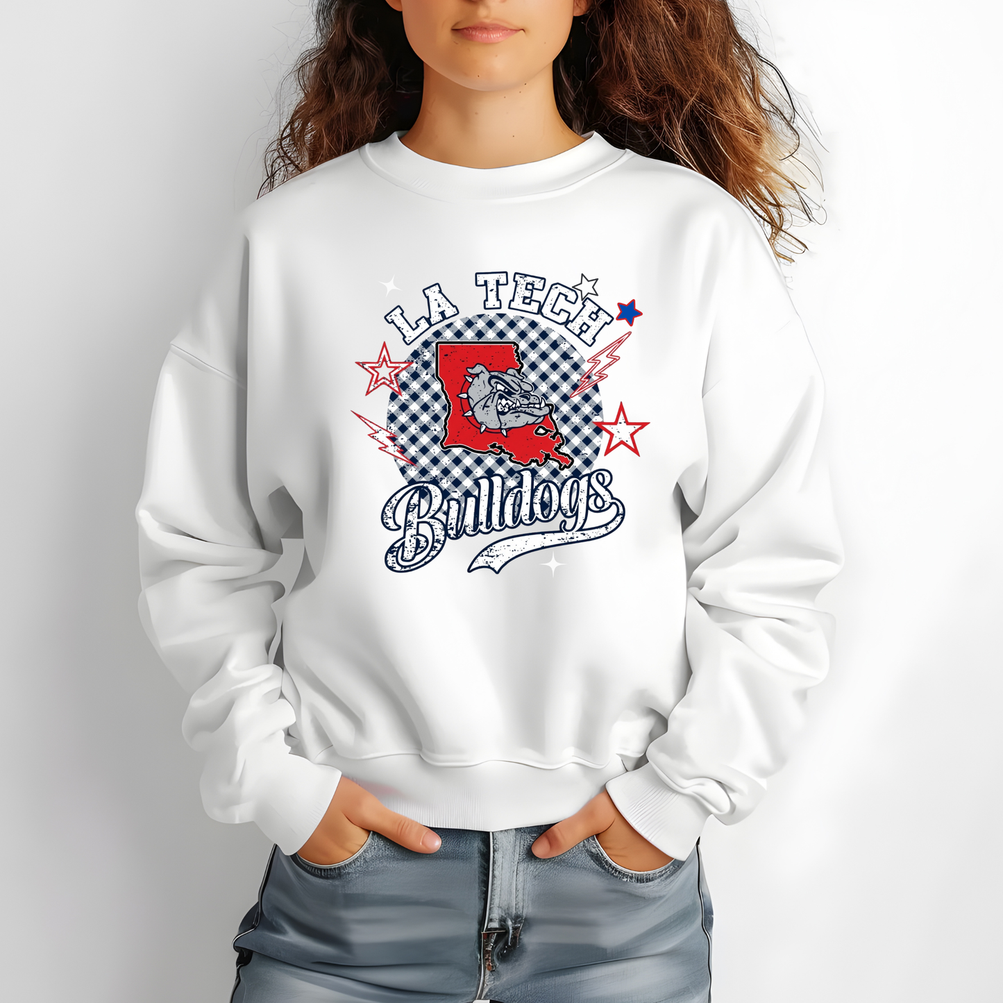 A woman wearing a white crewneck sweatshirt with a 'LA Tech Bulldogs' graphic on the front, paired with blue jeans, against a plain light gray background.