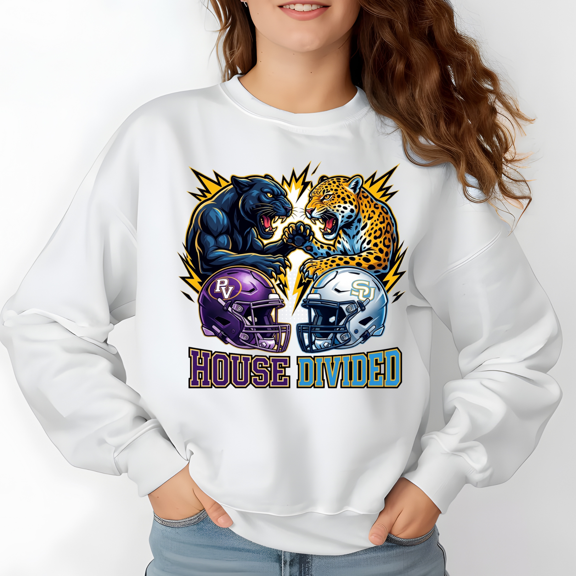 A woman wearing a white crewneck sweatshirt with a colorful graphic of a black bear and a leopard facing off above two football helmets, with the text 'HOUSE DIVIDED' below.