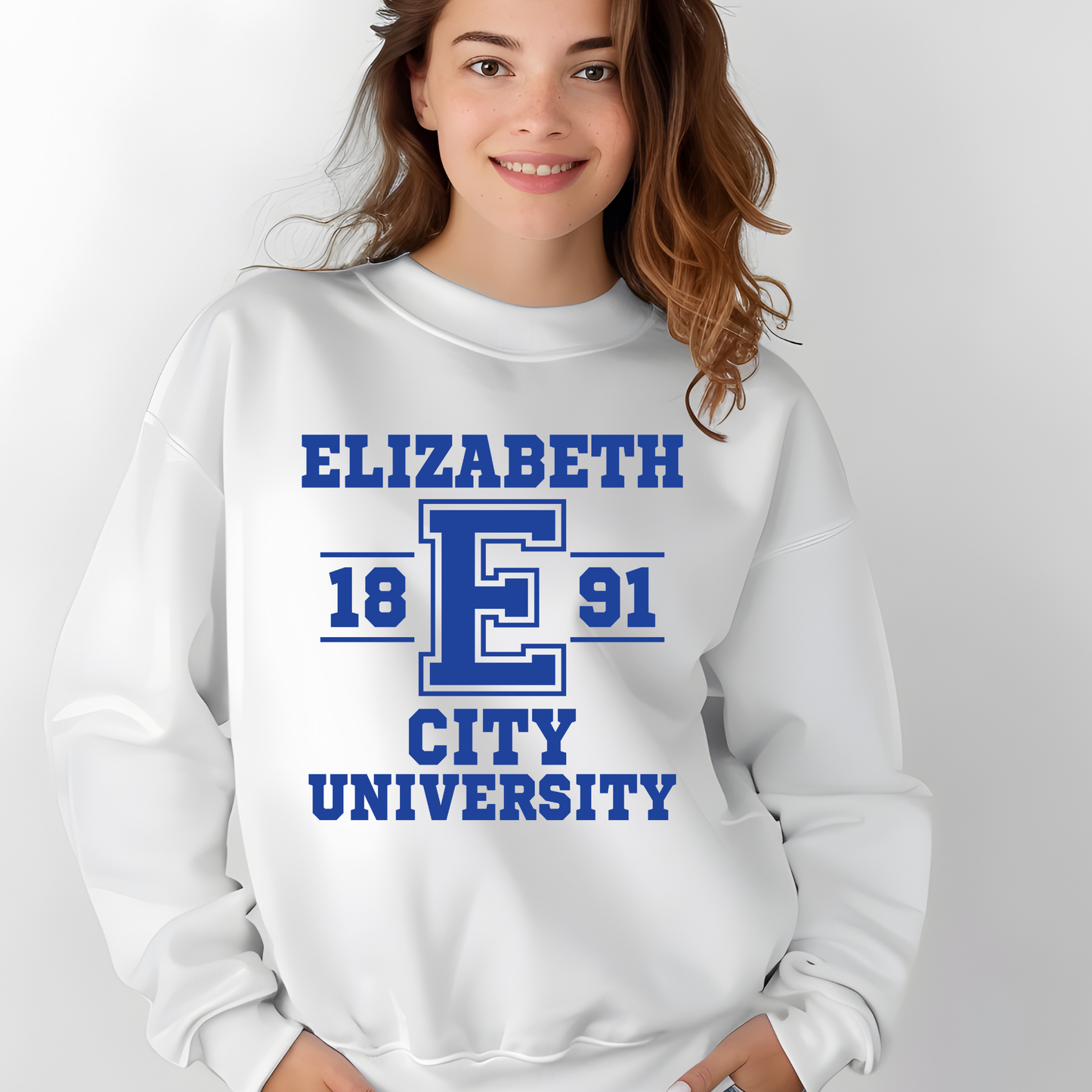 A woman wearing a white crewneck sweatshirt with a blue collegiate-style graphic that reads 'ELIZABETH 18 E 91 CITY UNIVERSITY'.